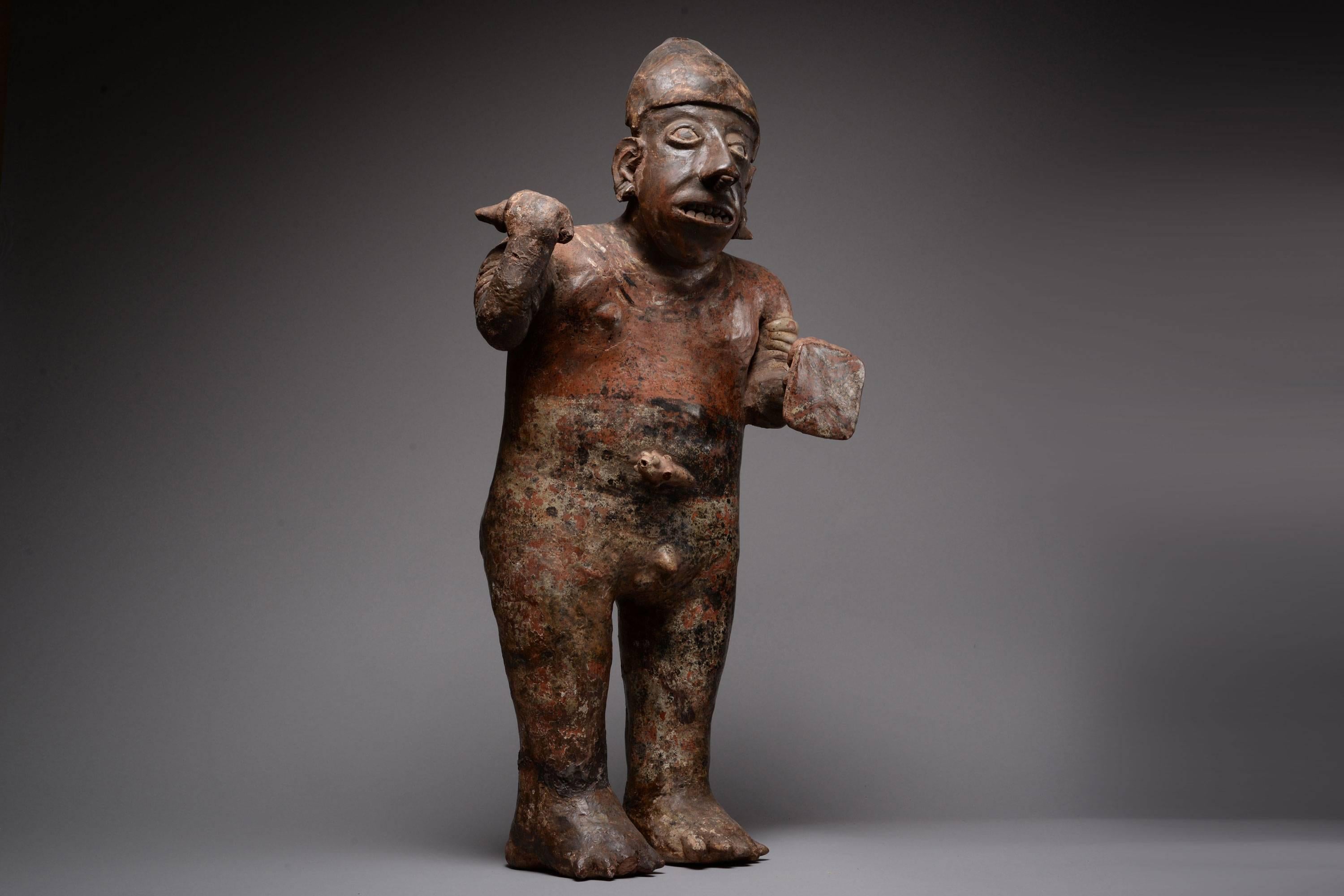 A well provenanced, large and imposing ancient pre-Columbian Nayarit terracotta figure of a warrior, dating to the Proto-Classic period, 100 BC – 250 AD.

The standing male figure is shown naked, coloured with a deep ochre pigment and wearing only