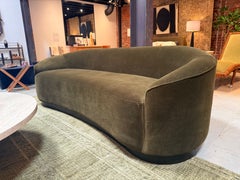 Geschwungenes Sofa aus moosgrünem Samt; stilvoll und bequem