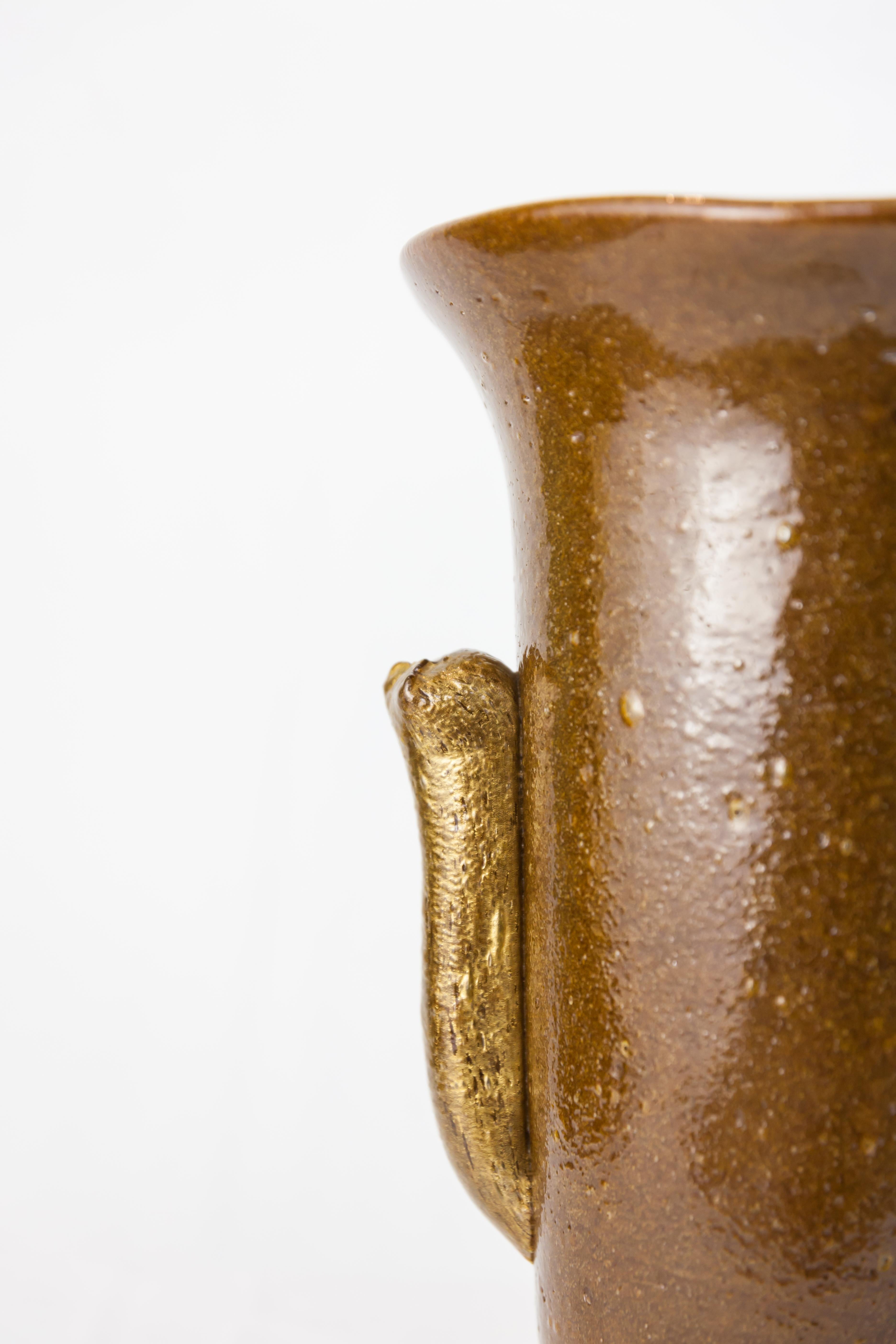 Vaso in vetro Pulegoso, circa 1930
Vetro Pulegoso marrone e oro.
Prodotto a Murano, Italia.

Dimensioni: 23 x 23 x 33 H cm / 9,1 x 9,1 x 13 H in

Il vetro Pulegoso, che appare pieno di bolle, si ottiene iniettando nel vetro fuso un componente che