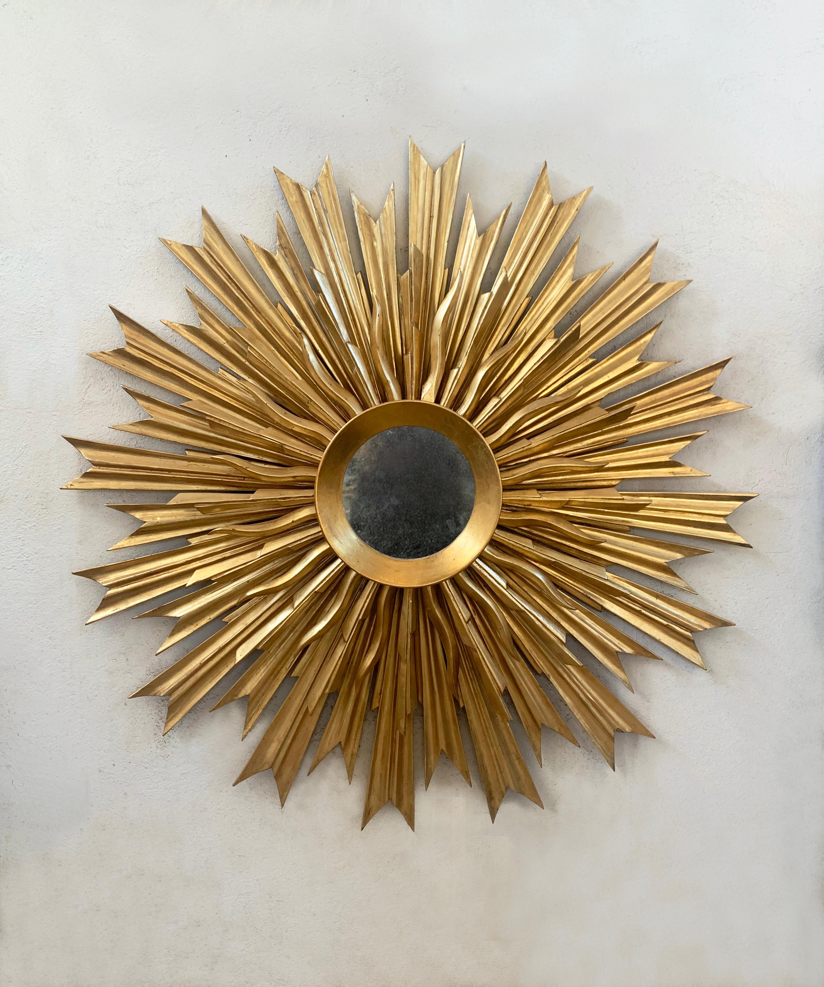 Stunning restored sunburst mirror from the last century, showcasing timeless elegance and exceptional craftsmanship. This exquisite piece is totally handcarved. It features a double row of meticulously carved wooden rays, all finished with original