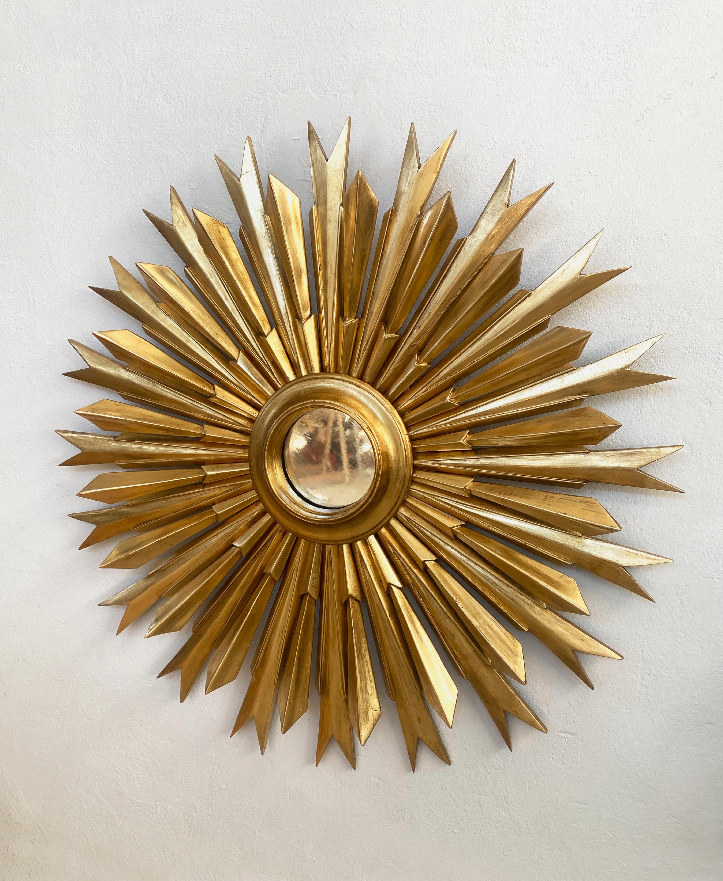 This stunning mirror is a newly designed piece, entirely hand-carved and crafted using traditional antique gilding techniques. It belongs to the refined category of golden sunburst mirrors and features a unique combination of two different types of