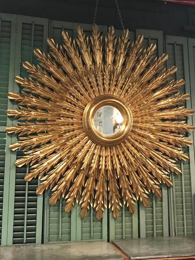 Magnifico specchio dorato a raggiera. Questo squisito pezzo è stato interamente intagliato a mano e presenta due livelli di raggi in legno dorato, ognuno dei quali ha una forma unica per creare un design suggestivo e armonioso. Ogni raggio è stato