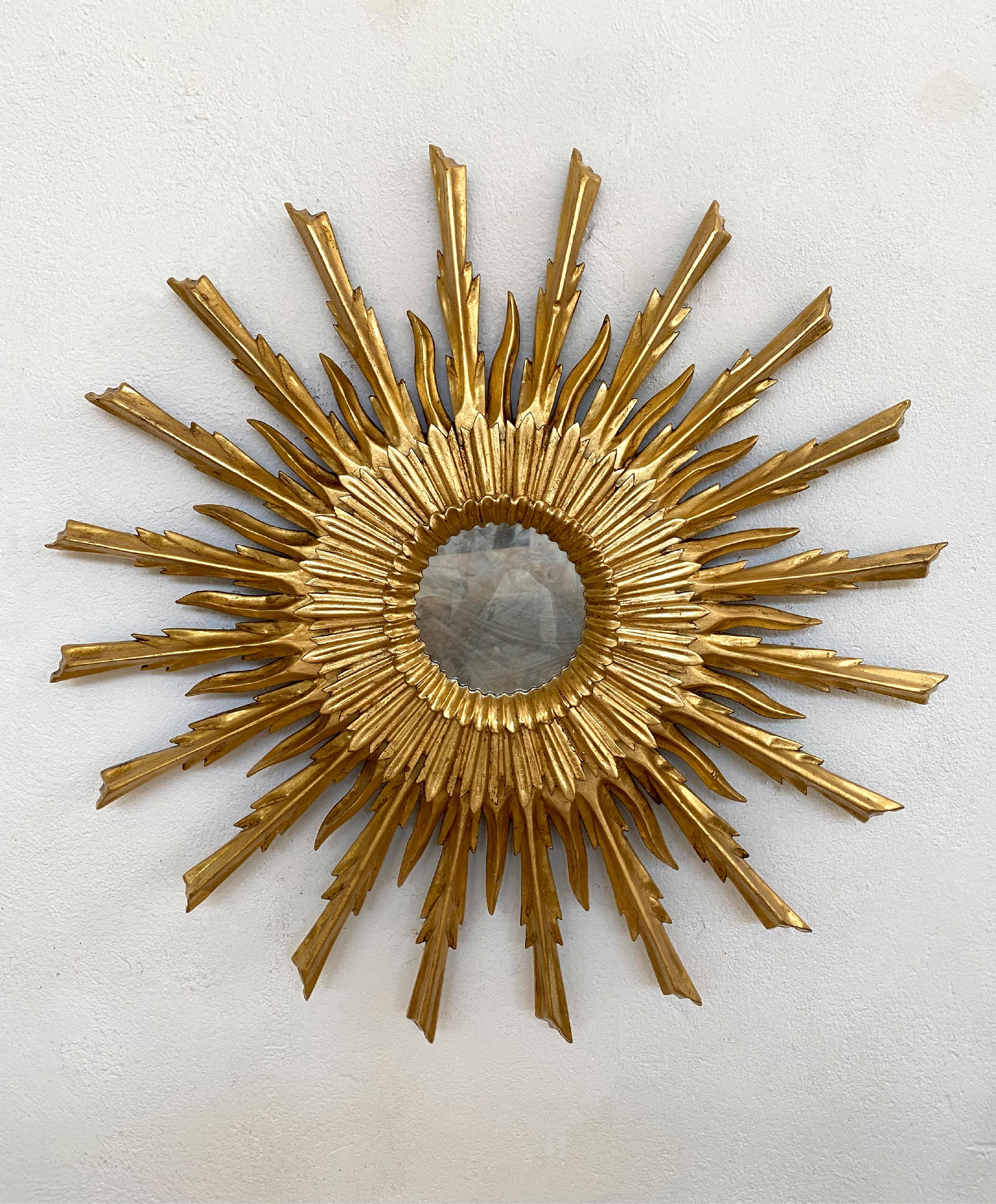 Specchio dorato d'epoca realizzato a mano. Composto da una doppia fila di raggi in legno dorato. Ogni raggio è stato intagliato singolarmente e ha ricevuto un trattamento artigianale basato su diversi strati di gesso e sulla lucidatura