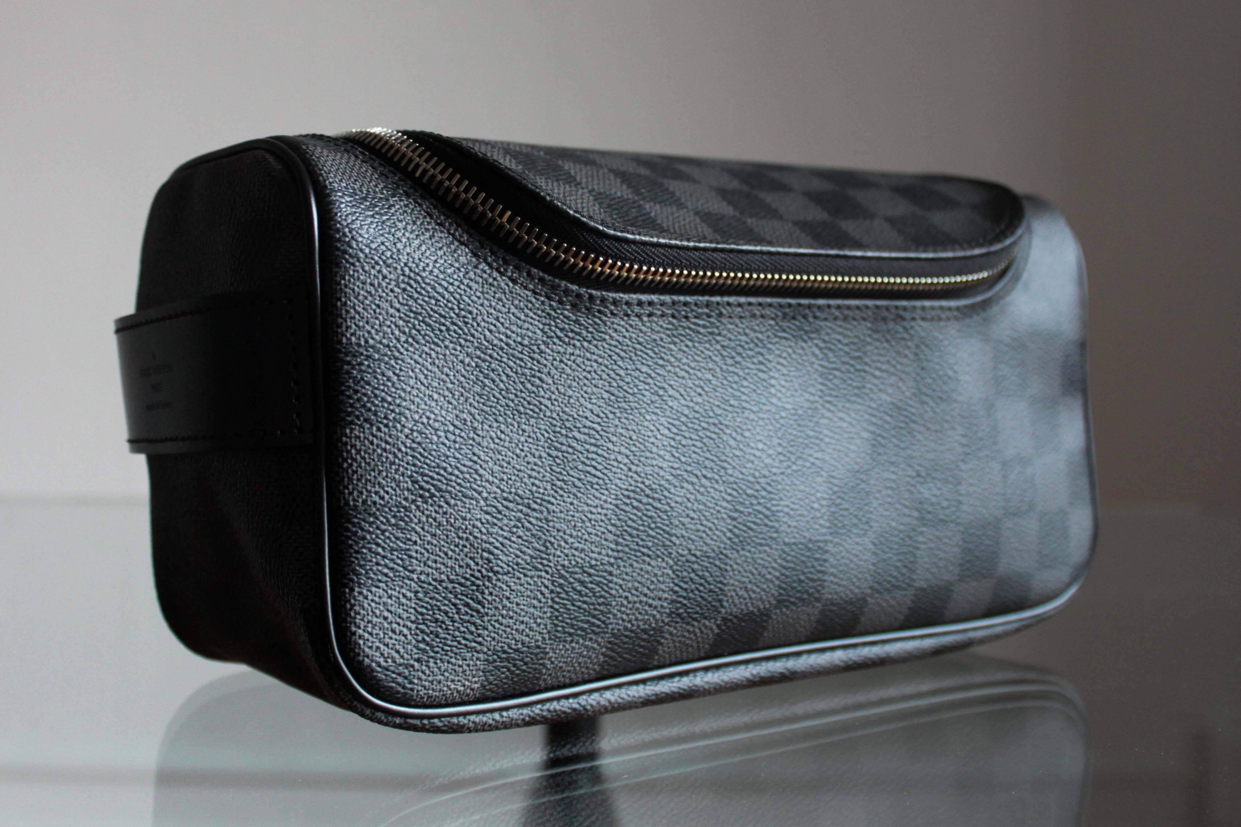 Toiletry pouch made from Damier Graphite canvas by Louis Vuitton. Interior has practical elastic attachments inside that will keep bottles vertical. As new condition, never used.