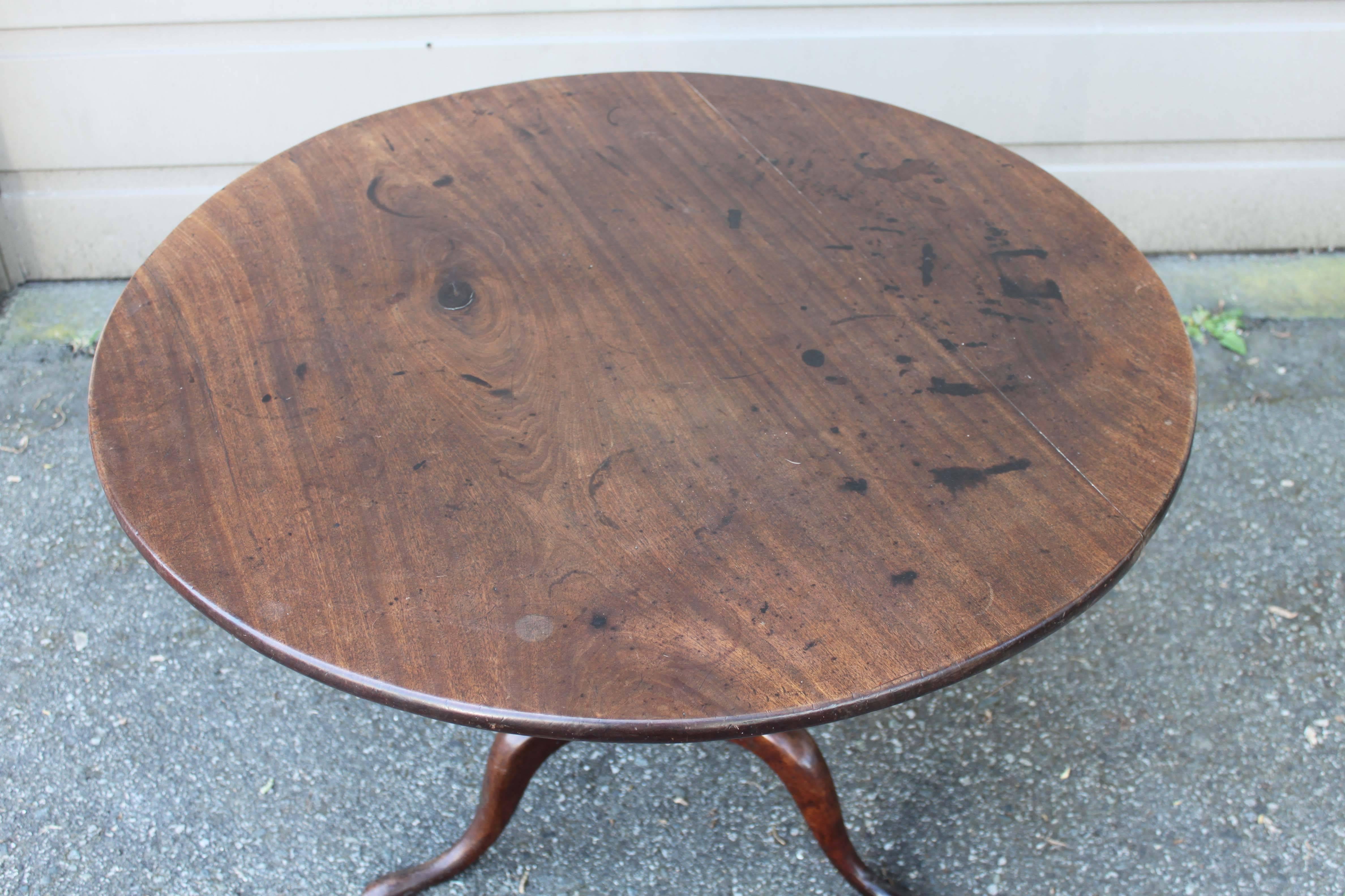 Mahogany tilt-top table in the Queen Anne style, circa early 19th century. Original hardware, note the wear and apparent age over the top surface.
