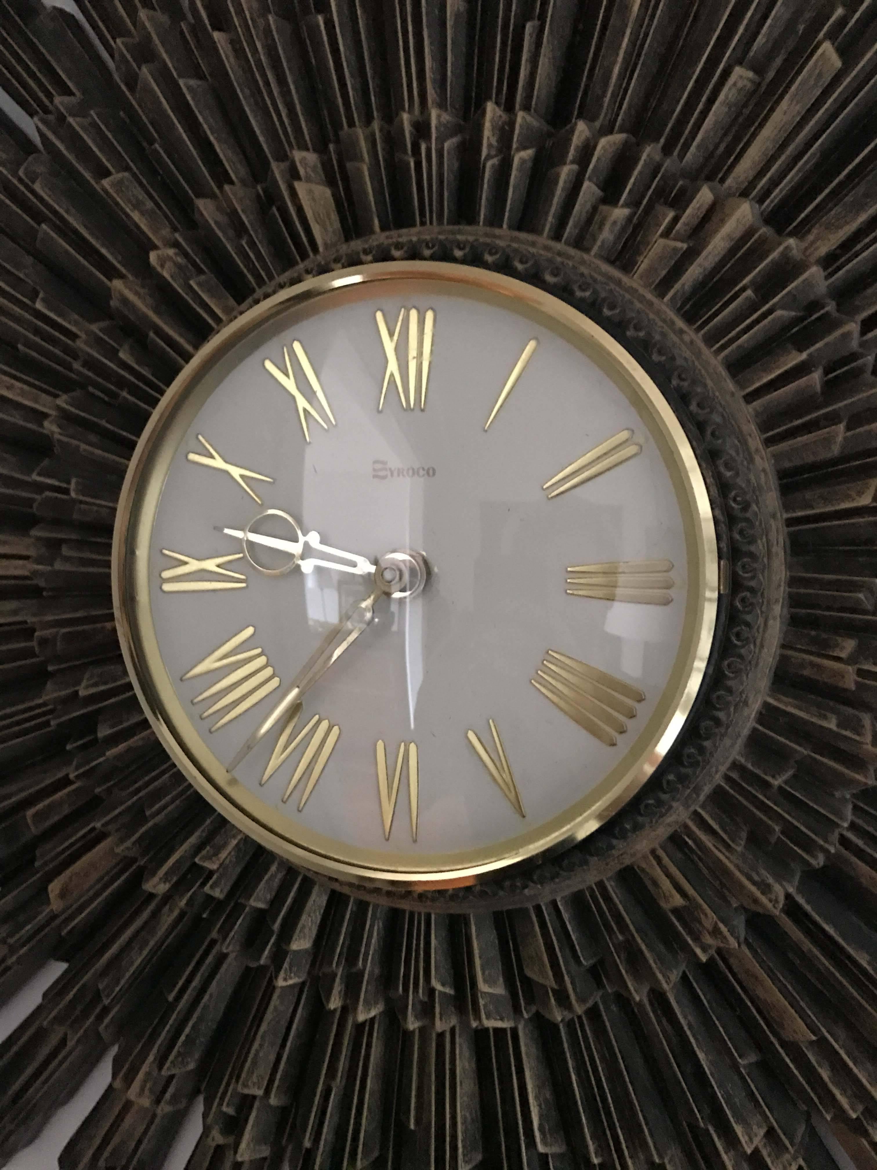 Vintage Syroco starburst resin wall clock in very good overall condition. Original mechanism is battery powered and functional, but will need servicing to tell accurate time. White face with polished brass and glass enclosure.