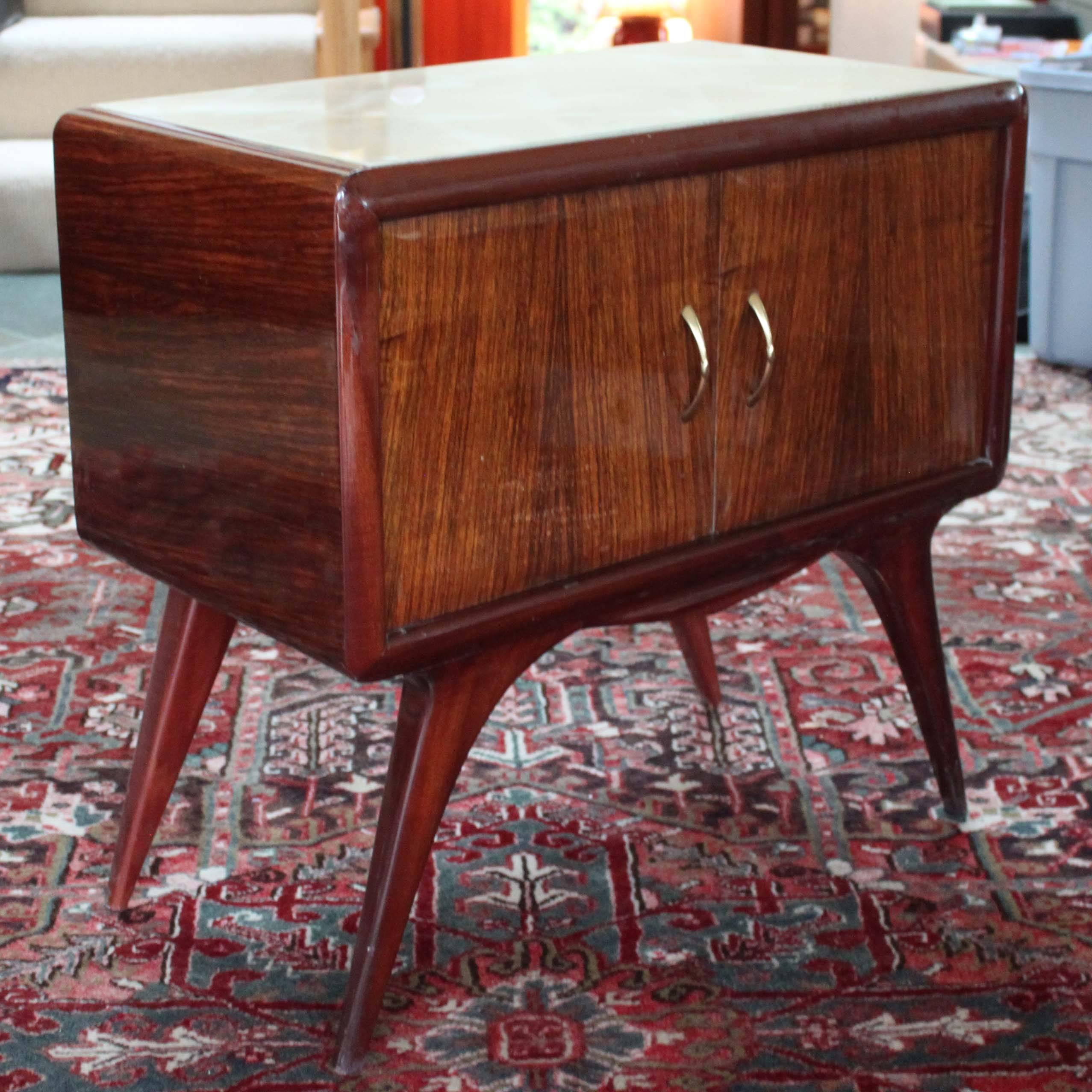 Mahogany side table attributed to Osvaldo Borsani in the modernist style. Original ivory tone glass top over a cabinet with brass hardware. Good overall condition with minor wear consistent with age and use.
