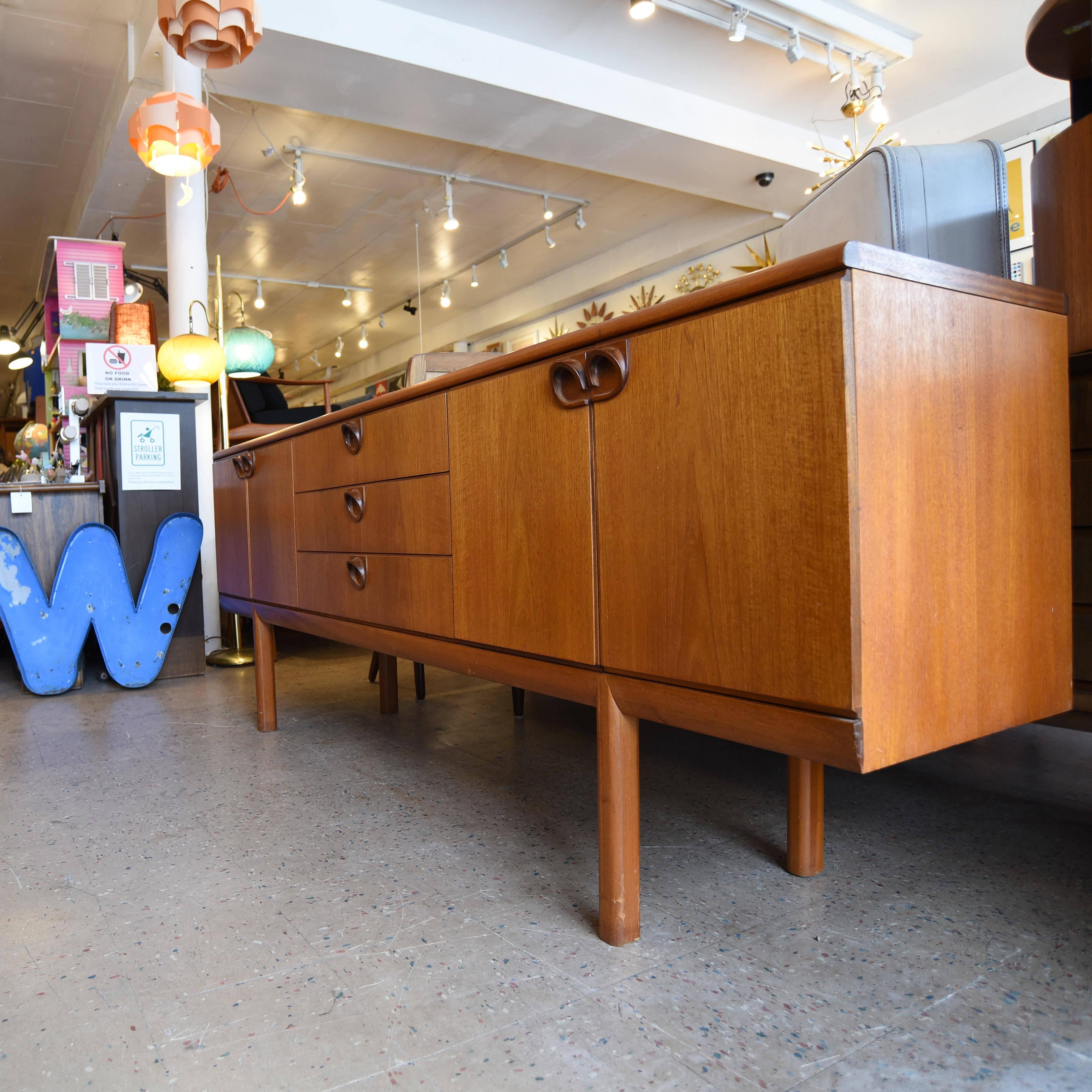 Teak credenza or sideboard signed A.H. McIntosh & Co., Kirkcaldy, Scotland.

The piece has unique modernist handles and a black sliding shelf in the bar compartment.

In great vintage condition.
 