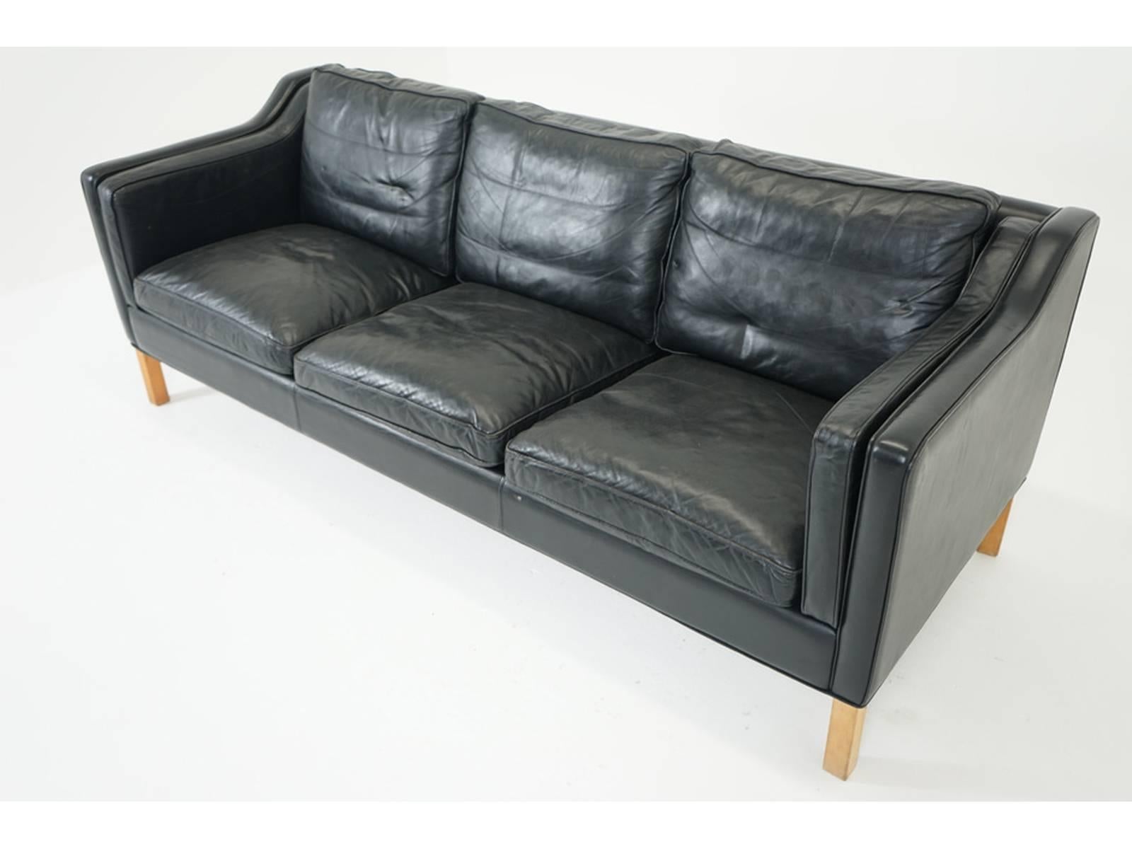 A stylish Mid-Century Modern sofa from Denmark. Original black leather in very good vintage condition, no rips or tears. Wooden frame is solid. Overall surfaces minor, normal wear consistent with age and light use, please see photos.