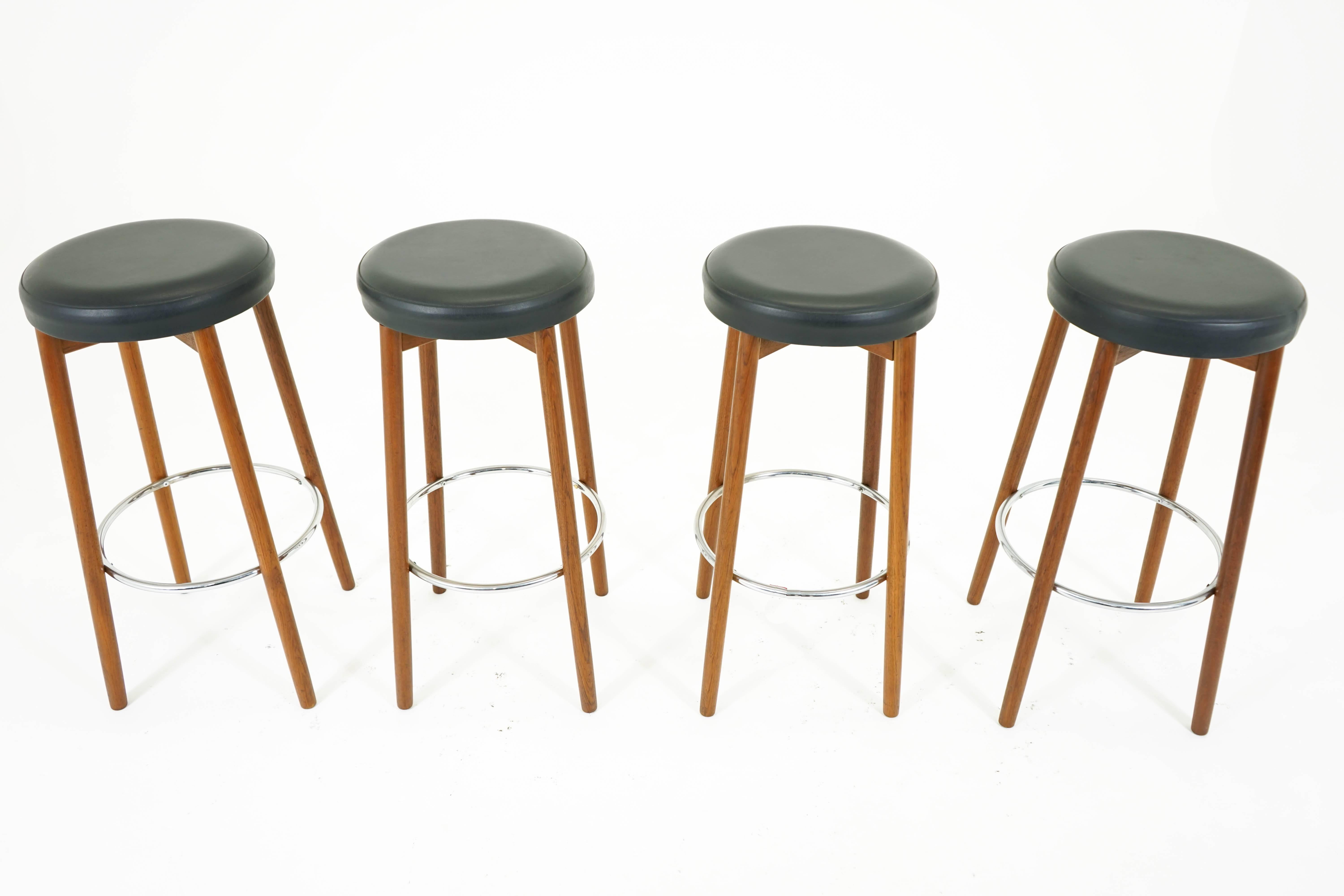 A set of four teak bar stools by Hugo Frandsen for Spottrup with chrome footrests and original leather upholstery. Solid construction in excellent vintage condition.