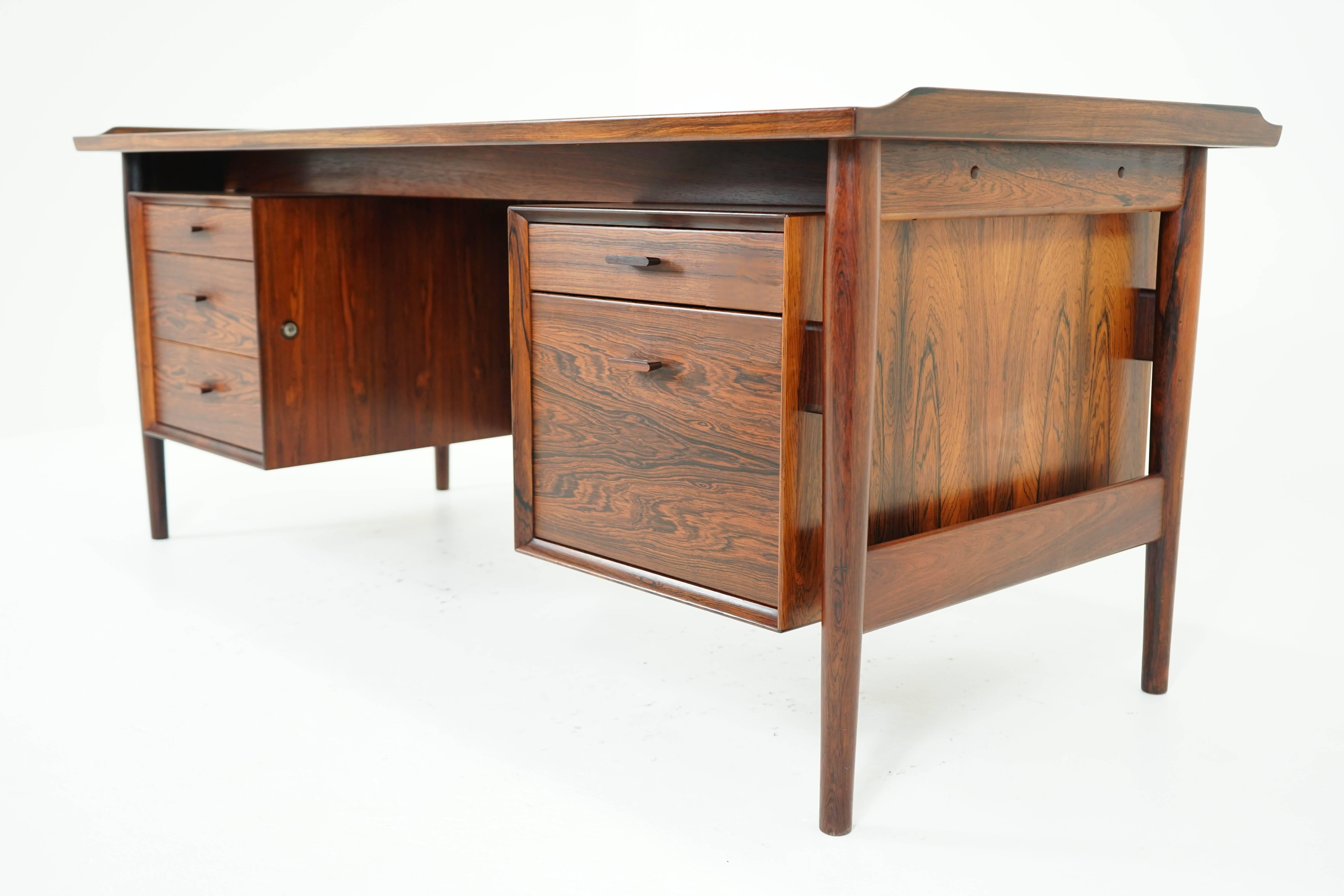 A Mid-Century desk, model 207, designed by Arne Vodder and made by Sibast Furniture. Solid wood and veneer construction with dovetail joinery, unique handles and original finish. Keys included, desk labeled "Sibast Furniture".