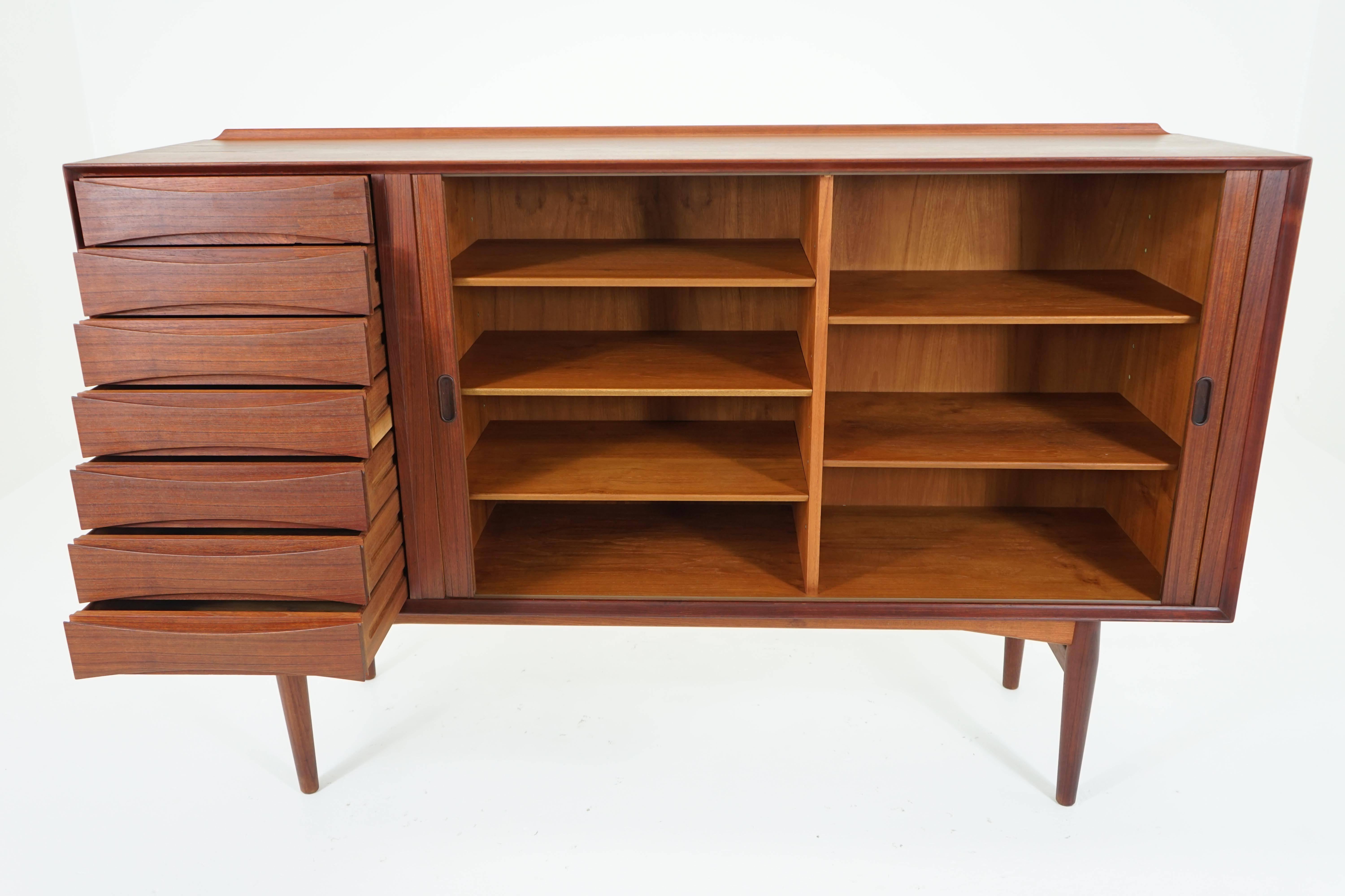 A beautiful solid teak and veneer sideboard by Arne Vodder for Sibast. Seven drawers and large cabinet with adjustable shelving. Original finish, made in Denmark, circa 1958.