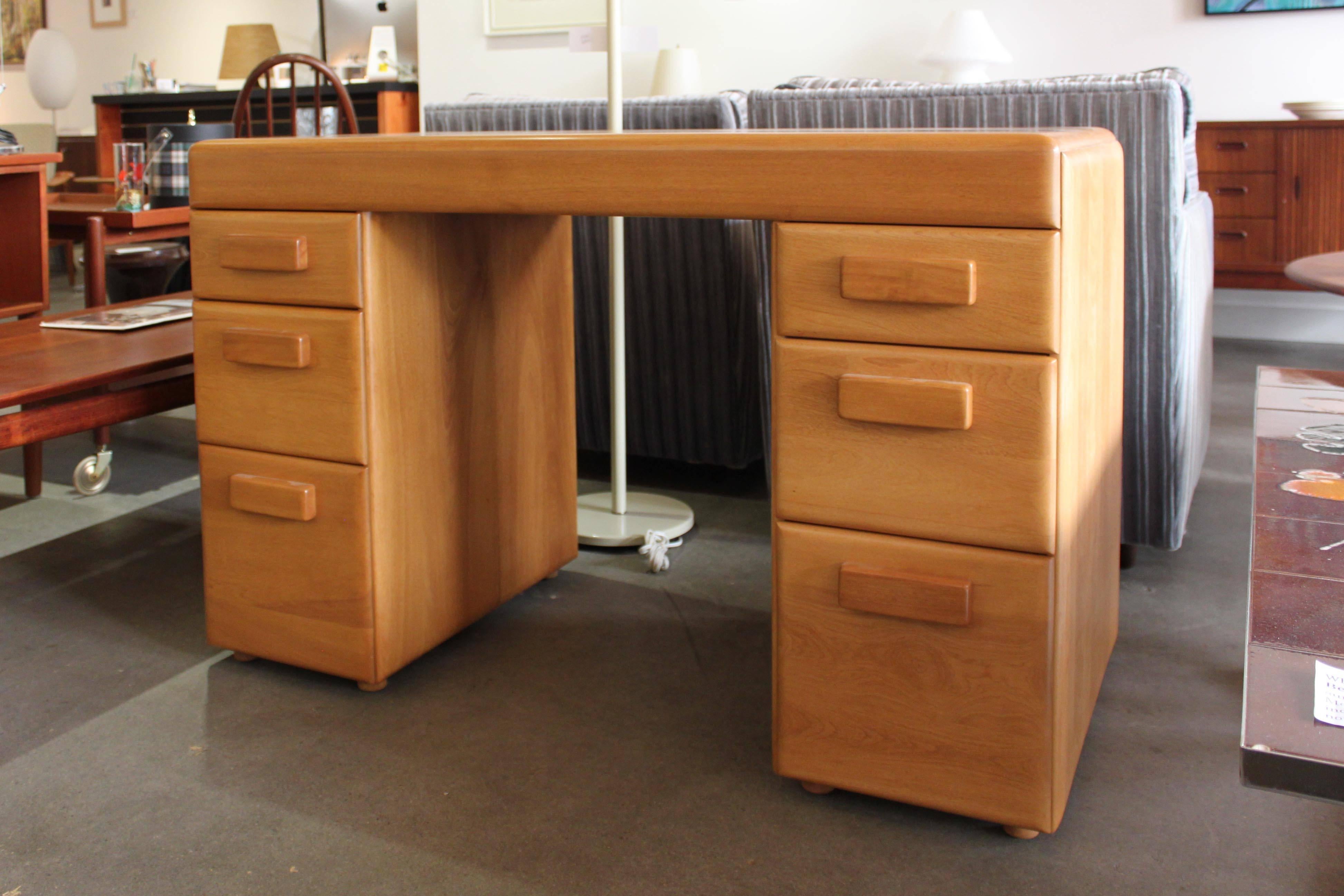 A desk made of made of solid birch by Russel Wright for the Snyder Brothers. Blending the Art Deco and Mid-Century styles, this piece was recently refinished and is in very good vintage condition. Please note the small area of discoloration on the