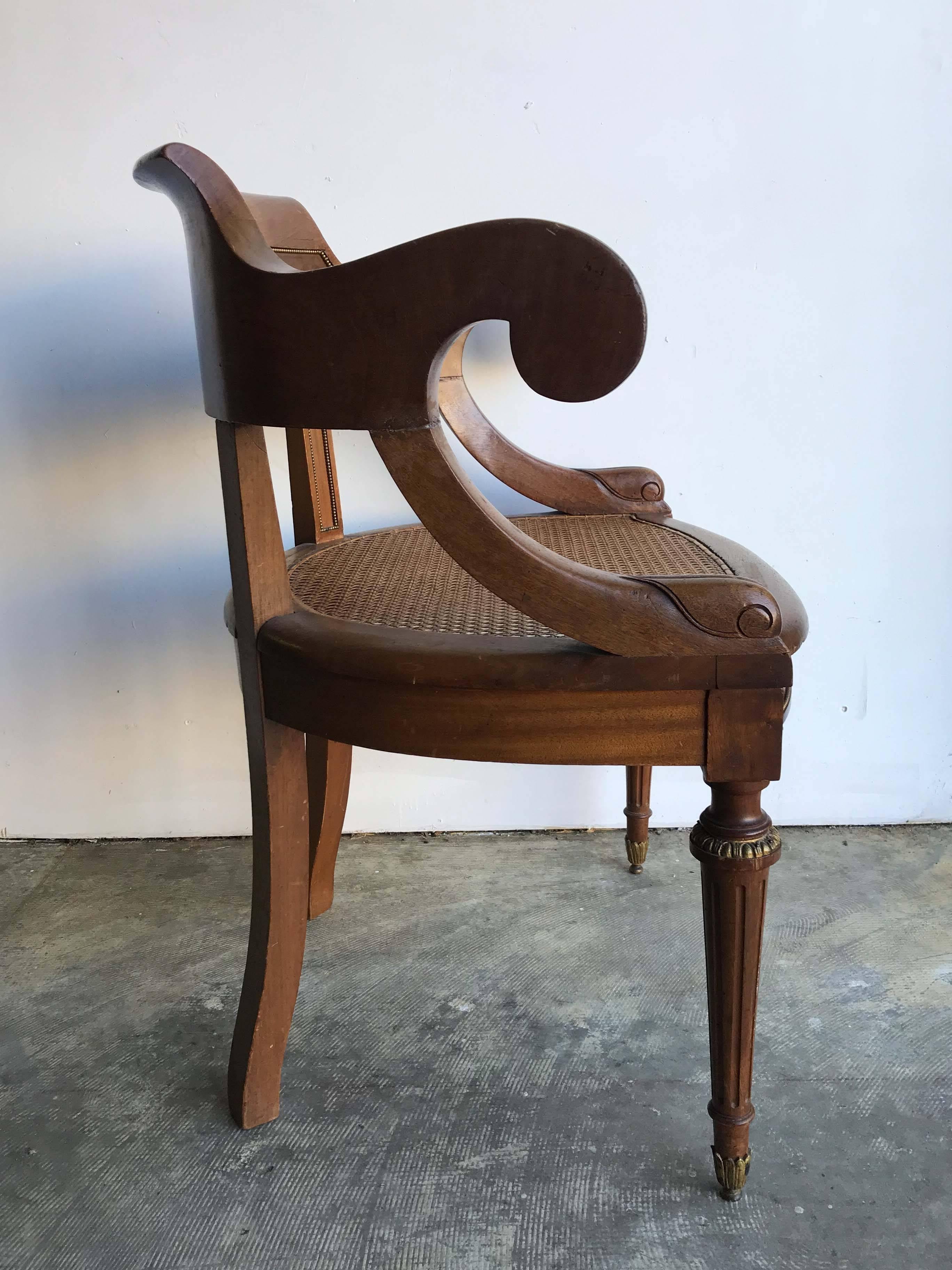 Antique French mahogany armchair with curved back and brass-trimmed recessed panel. Caning on seat in excellent condition.