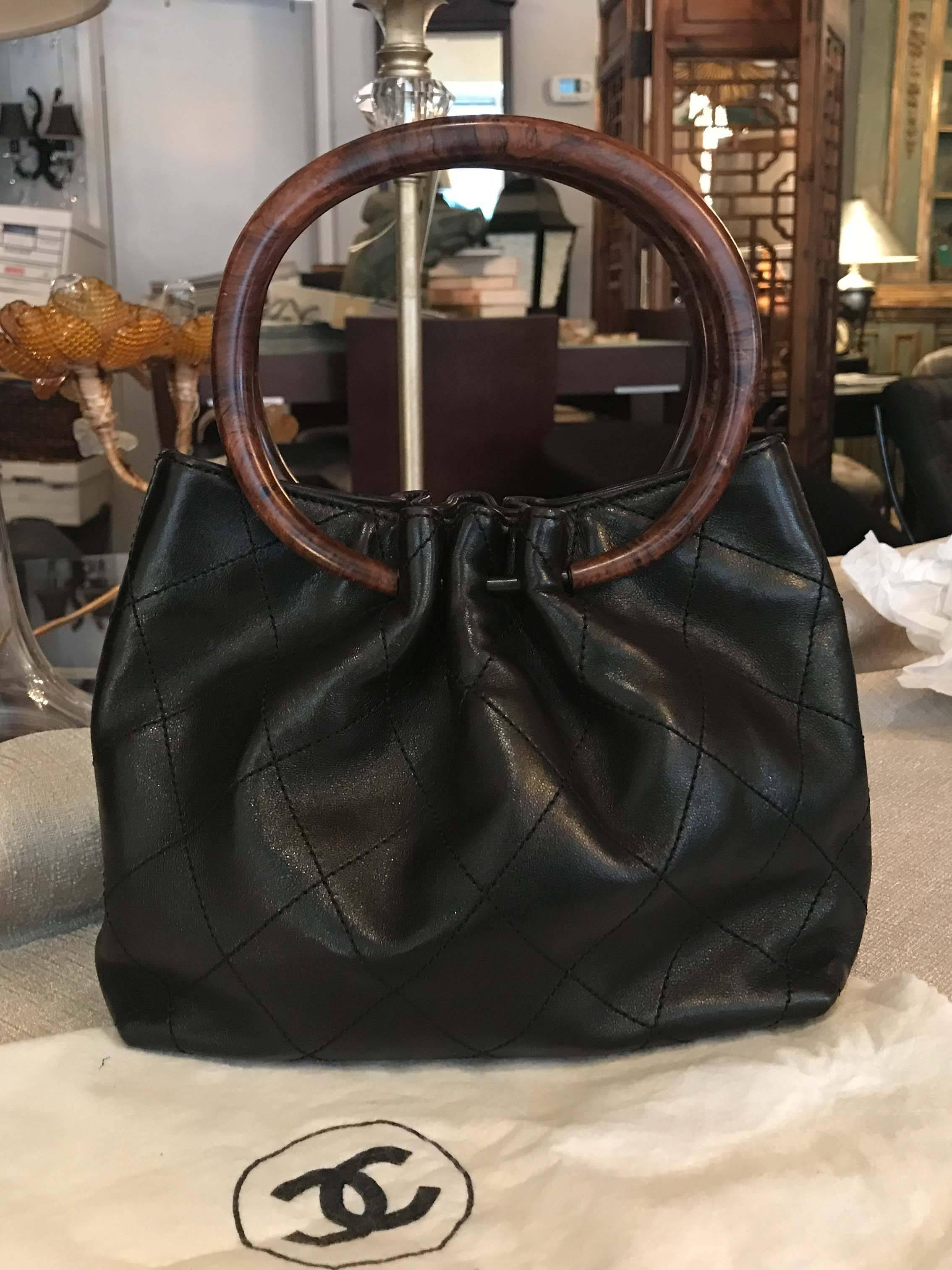 Black-brown quilted leather Chanel handle bag with gold-tone hardware, Dual marbled resin handles, black lining, zippered pocket and serial number on interior wall, magnetic snap closures at top. Light wear consistent with age and occasional use.