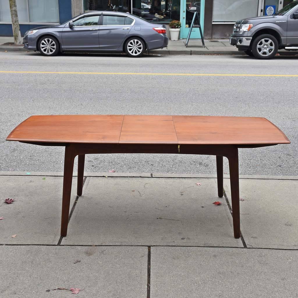 A rare Danish modern teak dining table with two centre leaves by Arne Hovmand-Olsen for Mogens Kold, model 217. Two leaves store underneath, in good refinished condition with minor wear consistent with age and use.