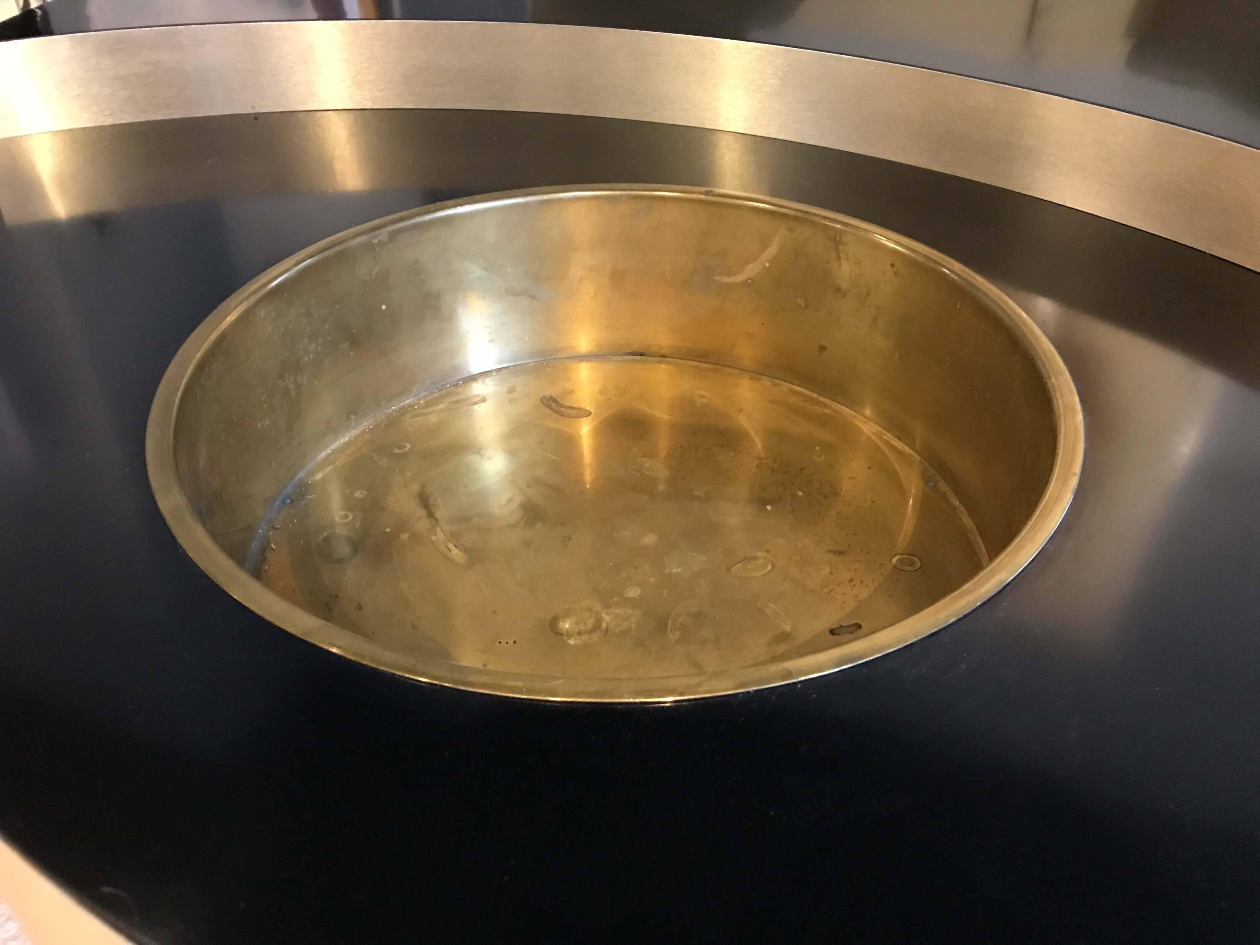 A revolving coffee table attributed to Willy Rizzo with brass trim and black laminate top. Note the areas where the brass is coming away from the laminate, please see photos. Table swivels with ease, functions well, in original condition. Unsigned.