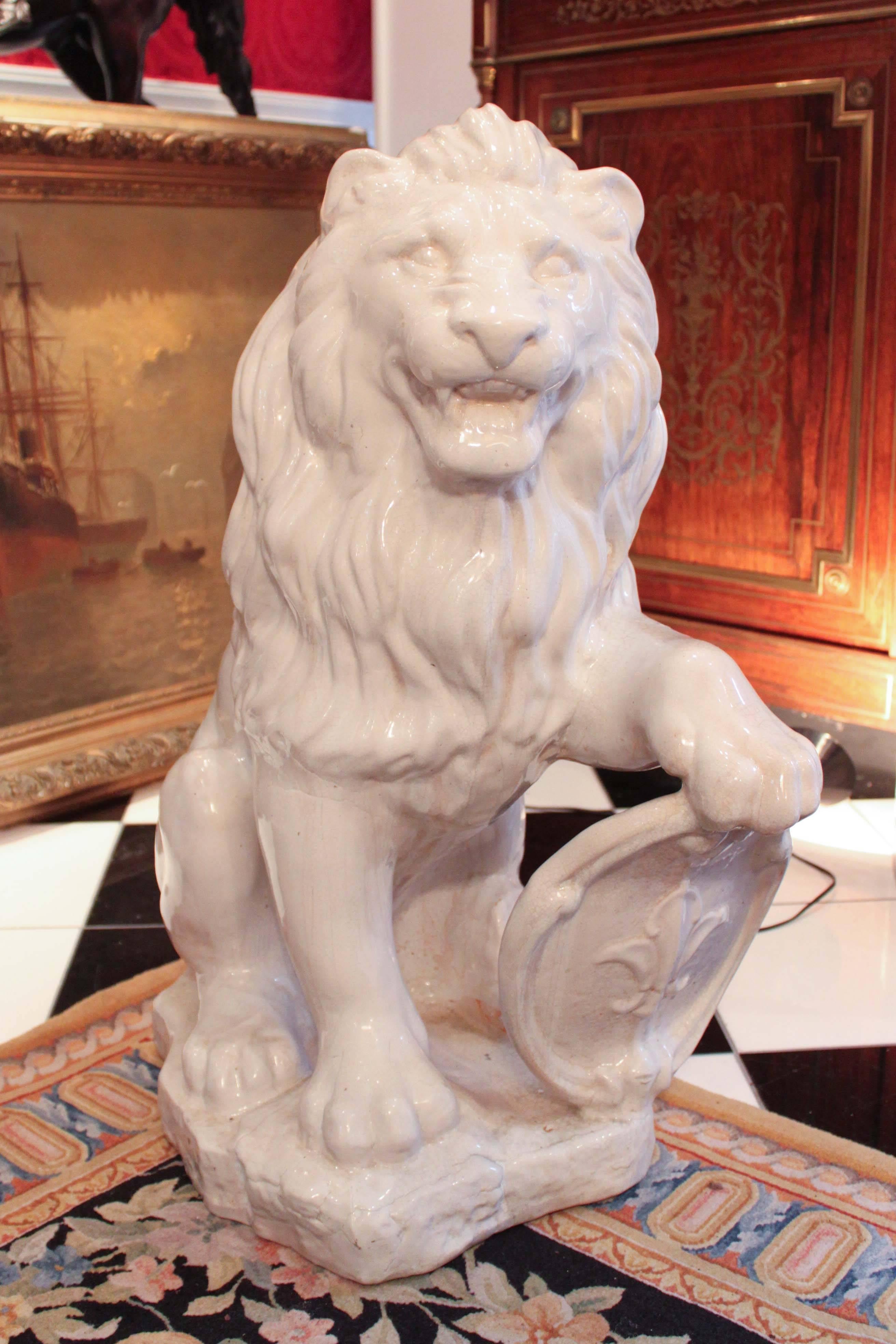 Pair of terra cotta lions in white, circa late 19th century. Great overall size and condition with minor hairline cracks typical for the age. Lions have an attentive and welcoming look on their face, with one paw on a shield with a fleur-de-lis