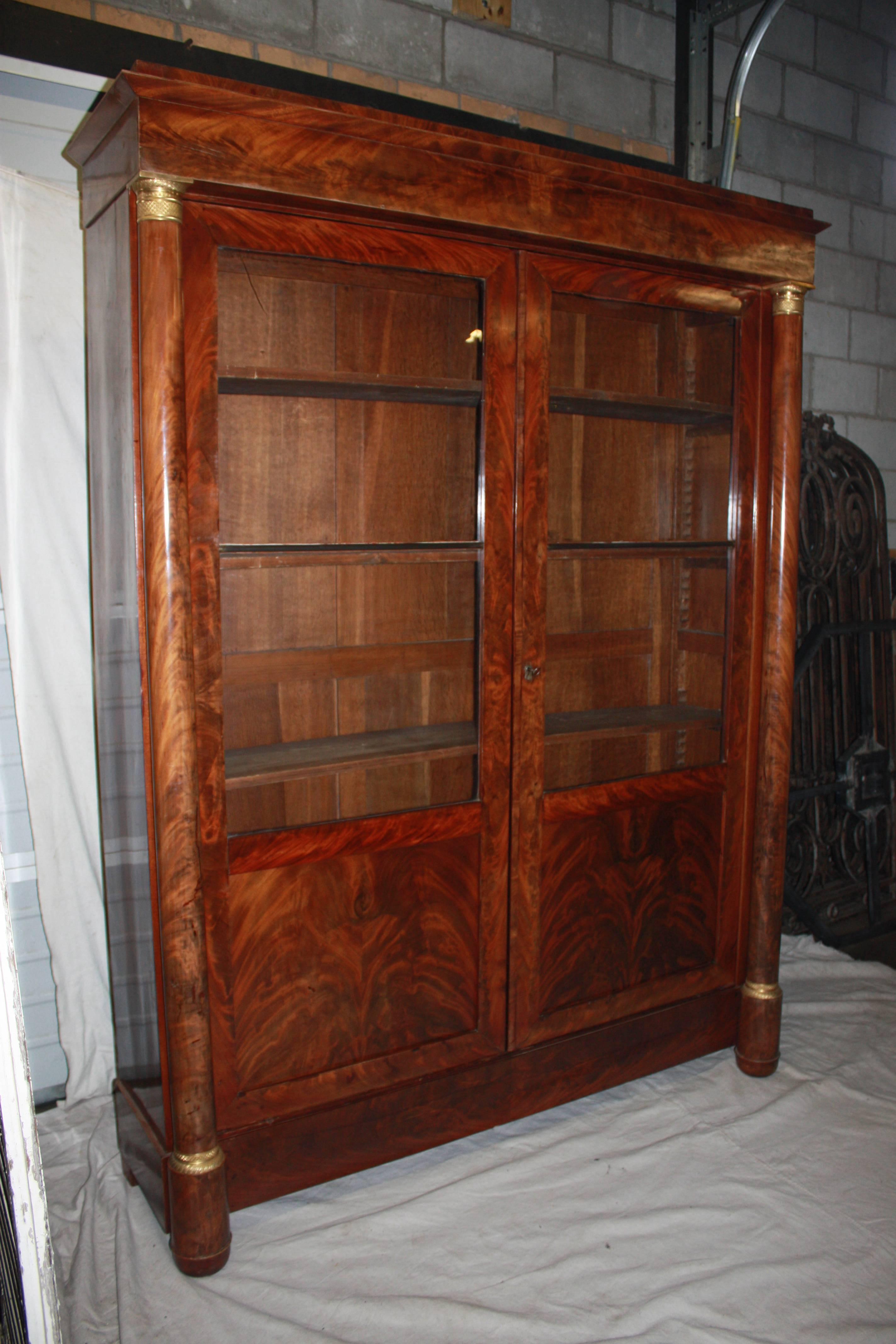 French Empire Period bookcase. Early 19th century, the bookcase wears a beautiful flamed blond mahogany marquetry. Original old window glass.
