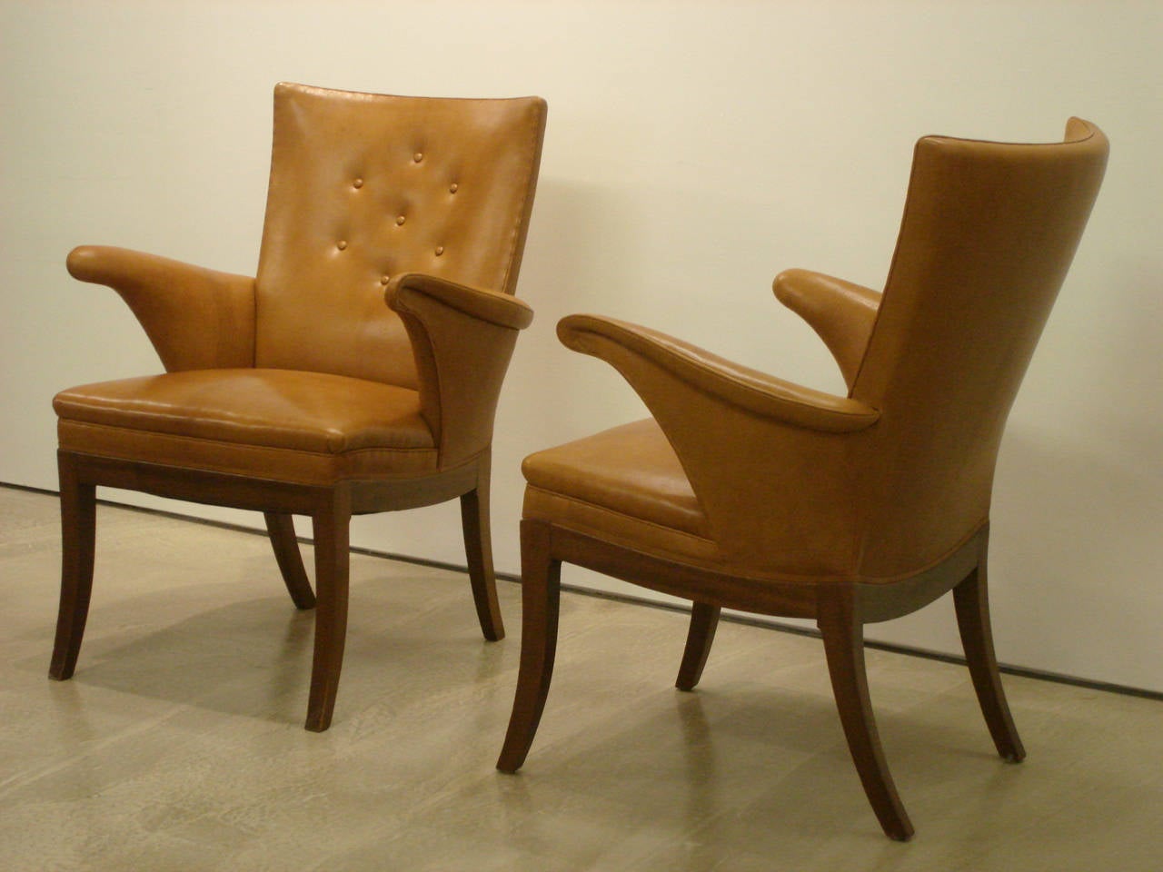 A pair of elegant armchairs with beautifully curved arms by designer and master cabinetmaker, Frits Henningsen. Upholstered in natural Nigerian leather, with legs of mahogany. Designed in 1935.

Sold as a pair. Single with Euro walnut legs