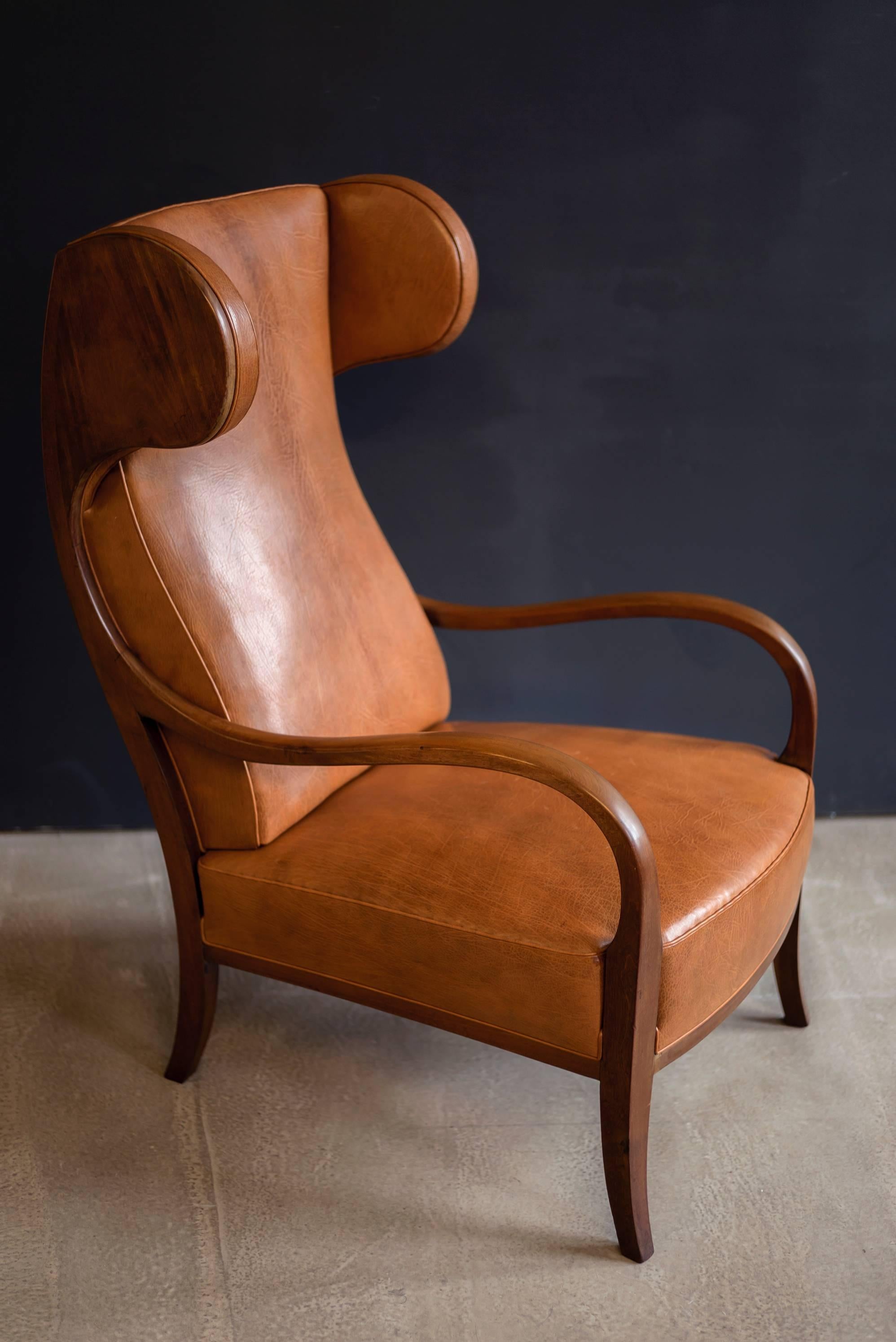 A large, elegant and sculptural 1940s wingback chair with sweeping arms and curved headrests. Frame of Cuban mahogany. Upholstered in Nigerian goatskin.