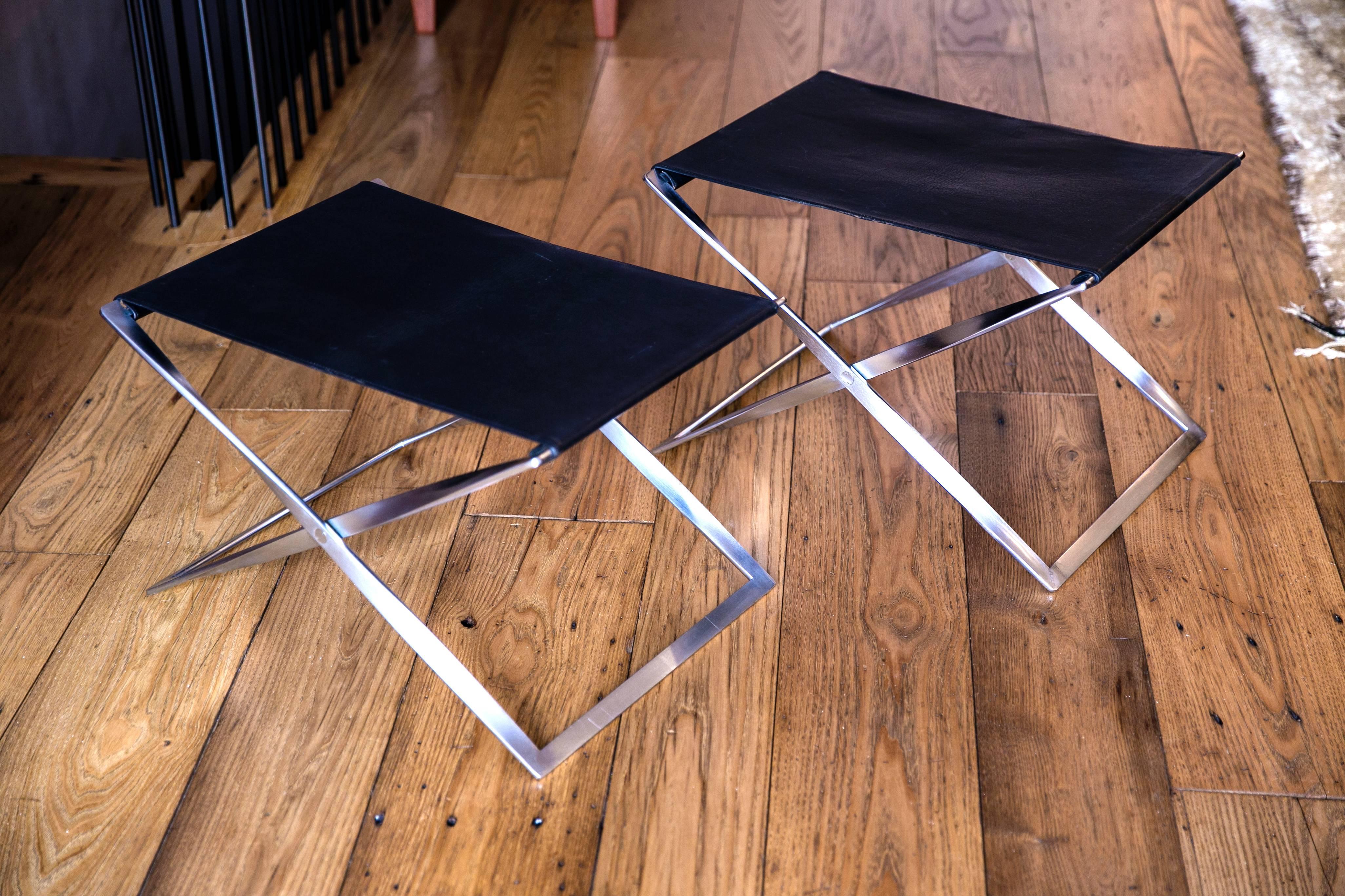 Pair of PK 91 Folding Stools by Poul Kjærholm for E. Kold Christensen. Made by E. Kold Christiansen.

Matte, chrome-plated steel, original black leather seats.

Designed in 1961, Kjærholm took inspiration for his folding stool from many places. He