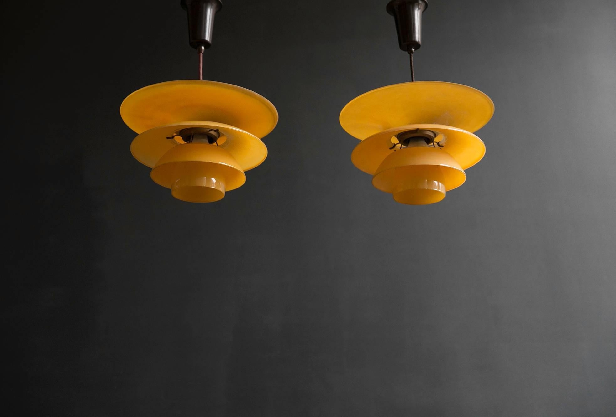 Poul Henningsen 4/ 3.5 /3 Four-Shade Pendant Lamps in Yellow Painted Matt Glass. A pair of Poul Henningsen pendants in yellow painted matte glass with bakelite sockets from the 1930s. Henningsen's four shade lamp in matte glass was added to Louis