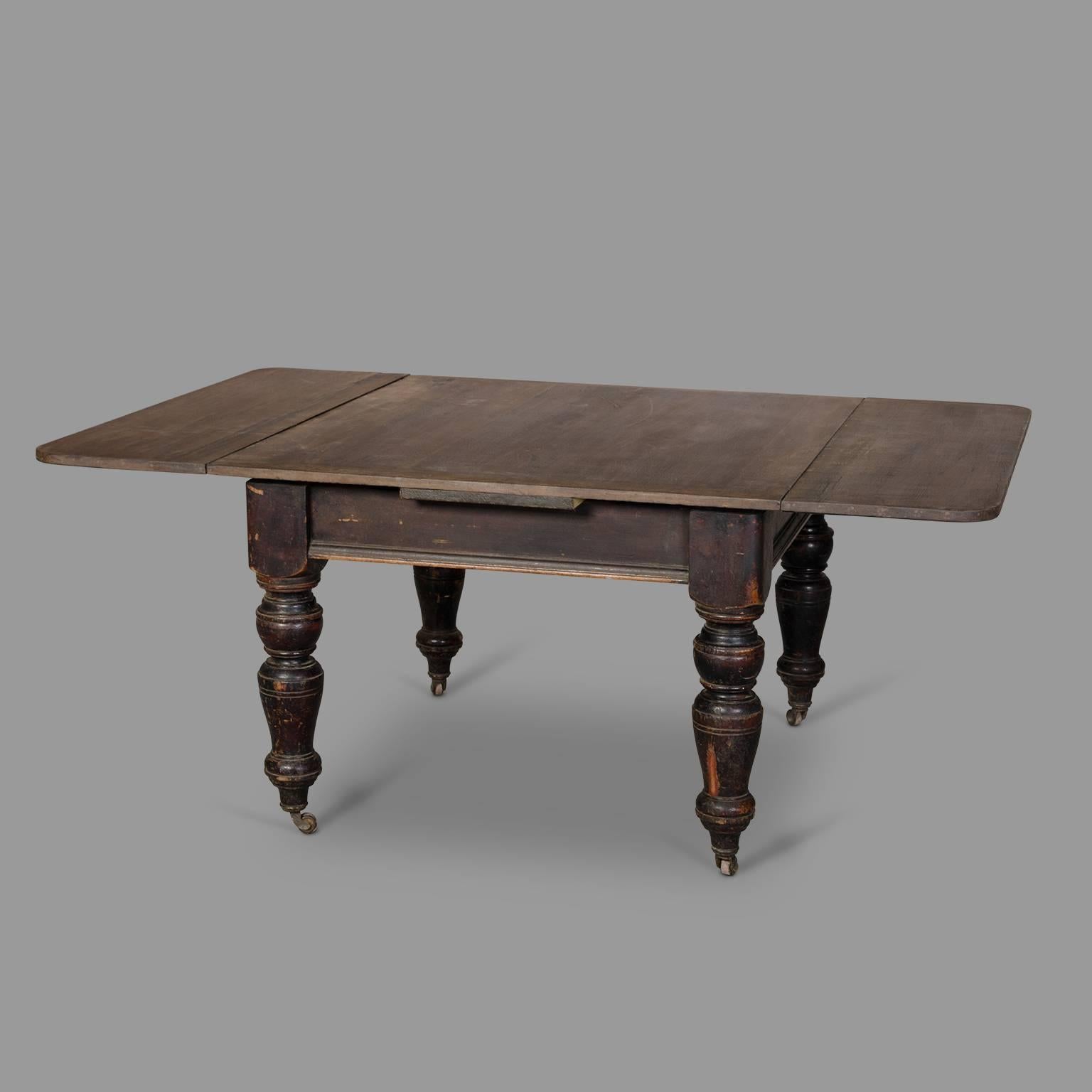 Popular work, Flanders between 1900 and 1930. Beautiful proportions for this table that combines solid turned wood feet and a top with a clever extension system. Beautiful waxed wood patina and remains of blackened varnish make it a very sculptural