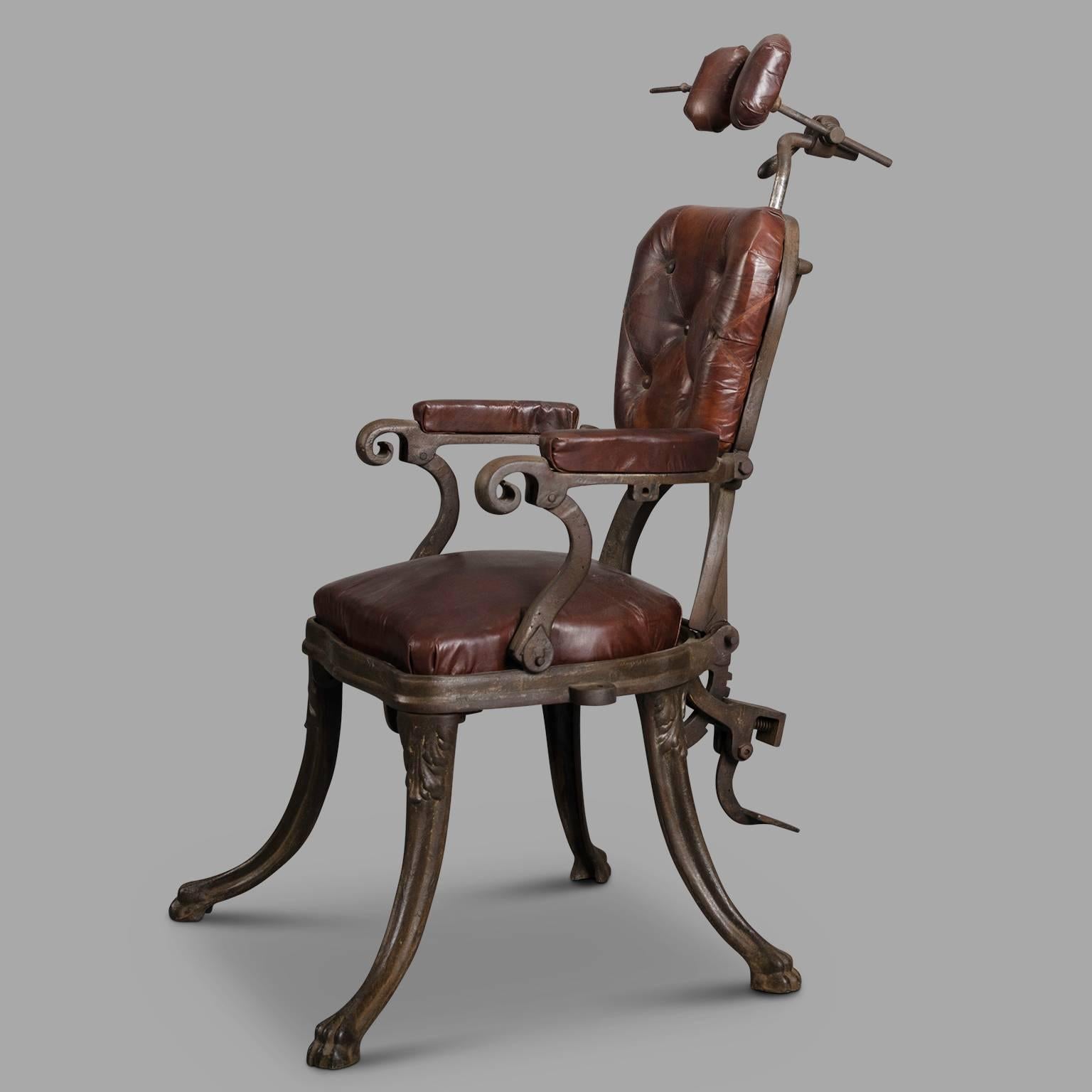 Early 20th century cast iron dentist chair. Backrest, seat, armrests and headrest in patinated leather. Pedal inclination mechanism on the back. The footstool is missing. Model inspired by that of Adam Schneider whose simplified mechanical met great