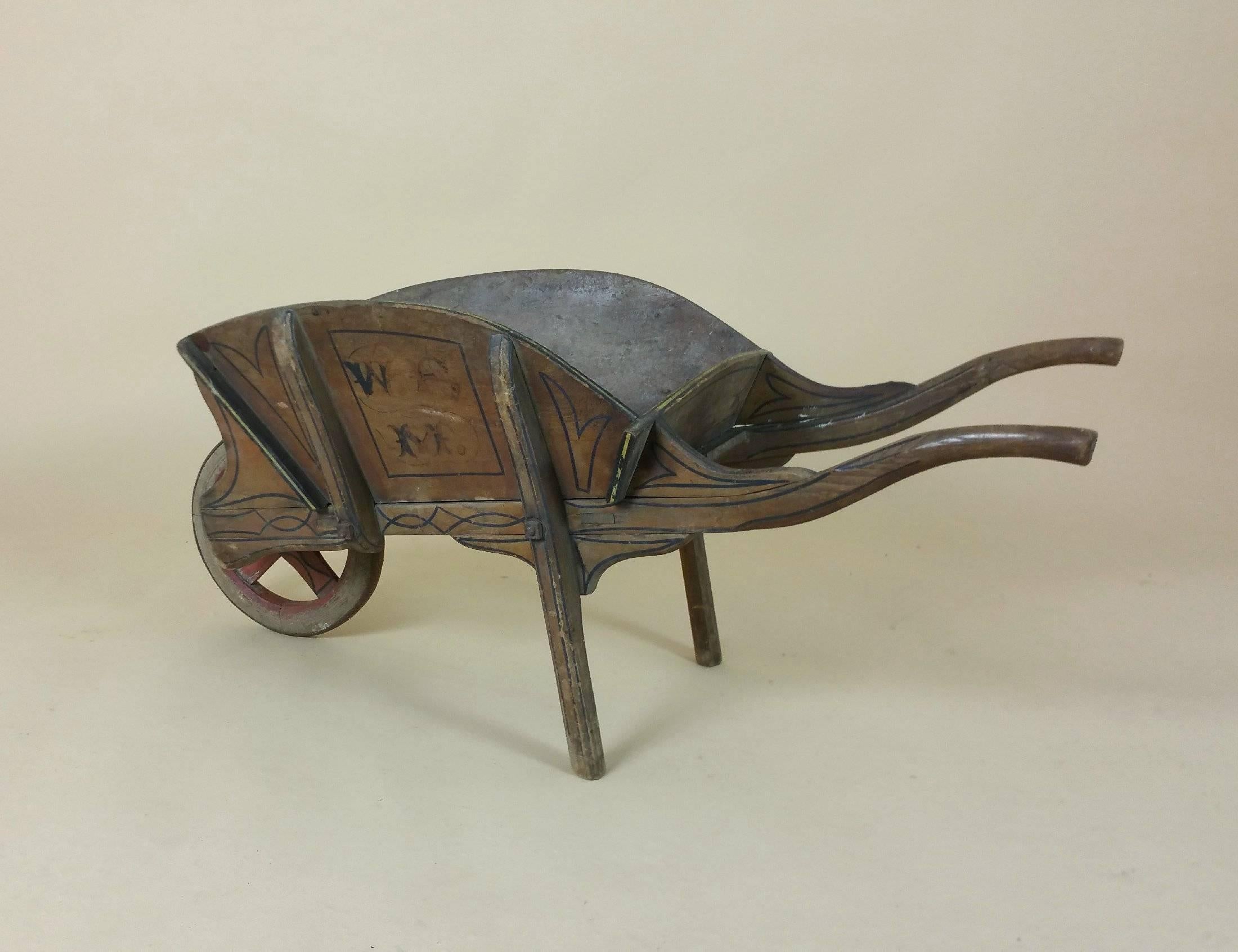 This absolutely enchanting and very rare early 19th century library book barrow is made of fruitwood that has been hand-painted and decorated with a monogram. The book barrow has a wonderful patina, worn and weathered, with a working front wheel. It