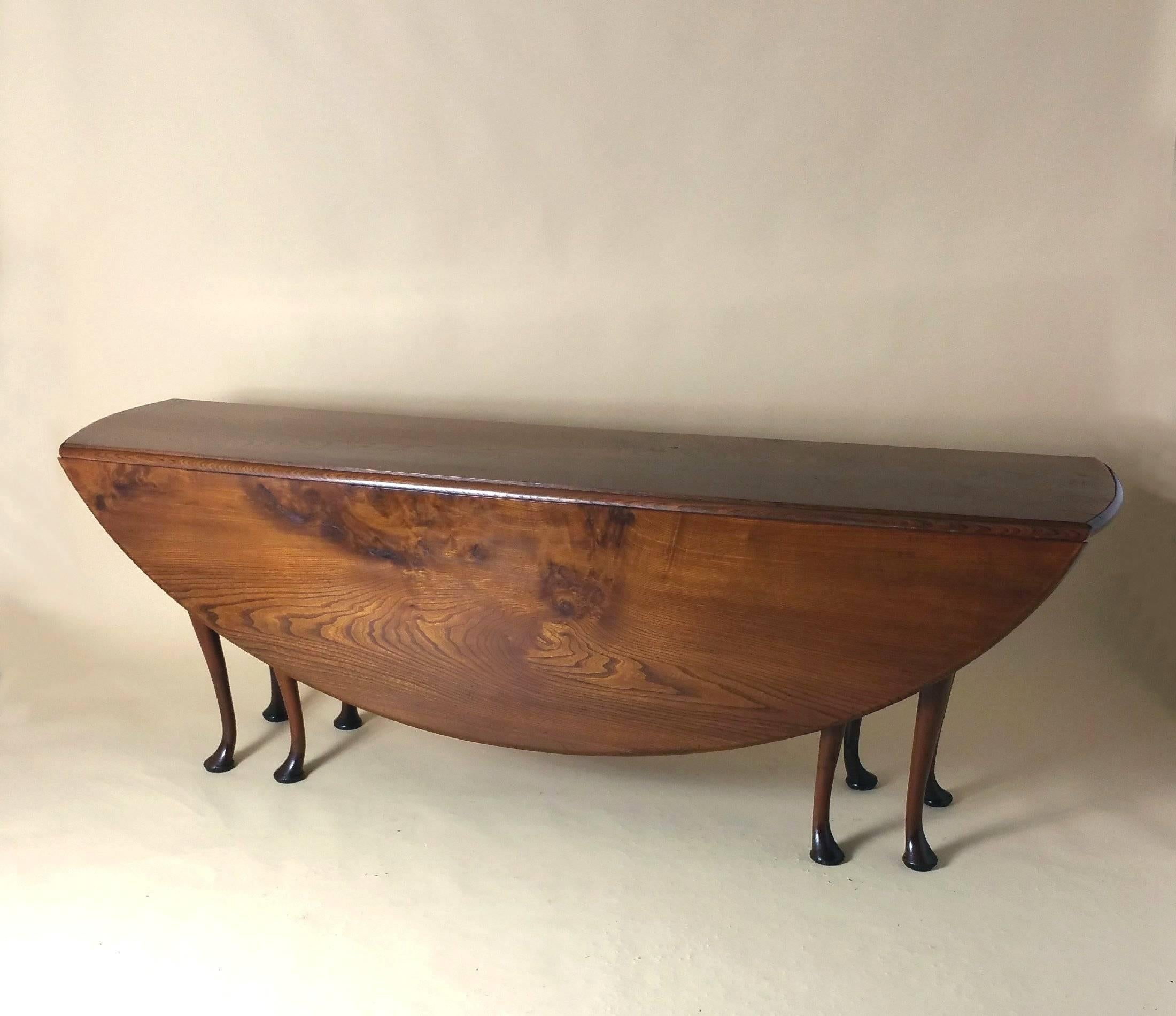 This splendid and solid mid-20th century drop-leaf wake table is made from pollard Elm, and is supported by eight yewwood cabriole legs. The table opens up to a more unusual long oval shape, which would accommodate eight-ten people. It measures 84