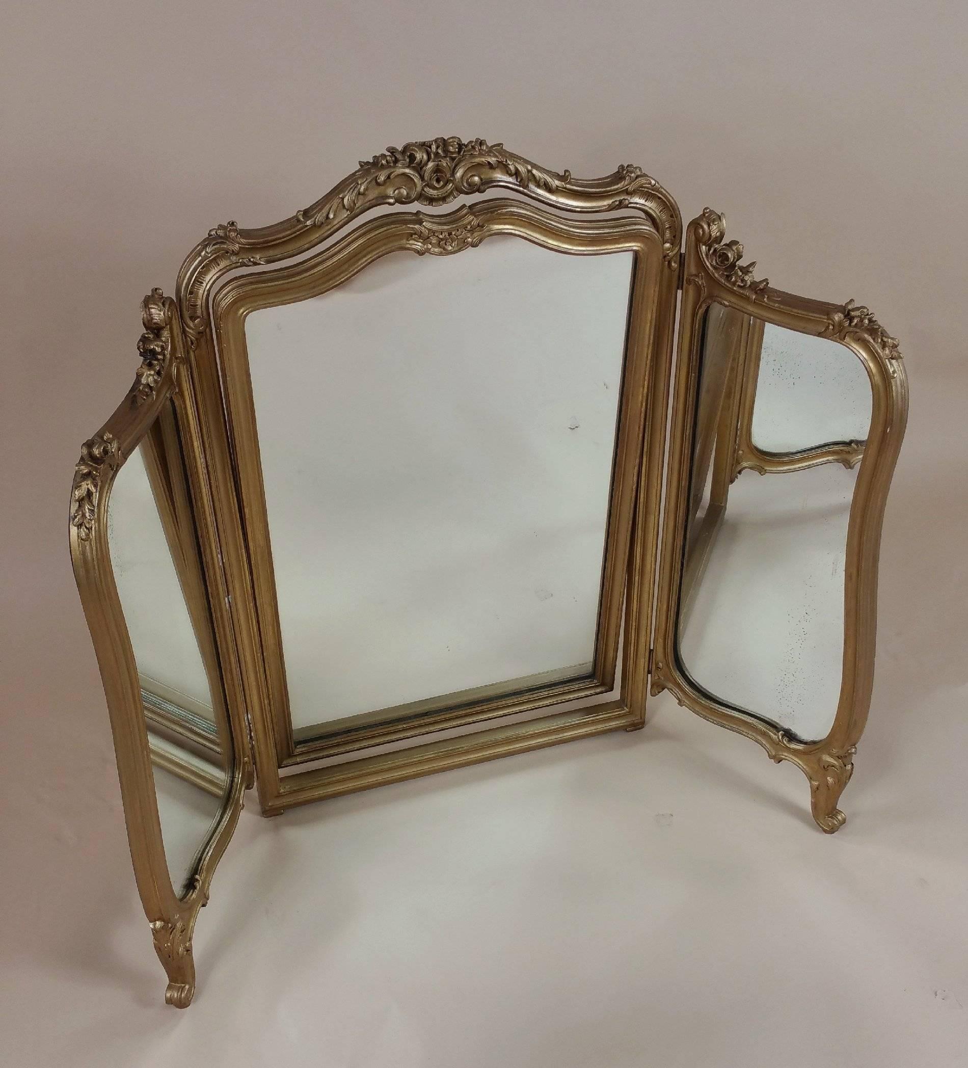 This beautiful and sizable 19th century carved giltwood triptych mirror will fold together completely, in addition to the fully tilting central mirror. The English piece features a lovely serpentine shaped top and is supported on curled acanthus