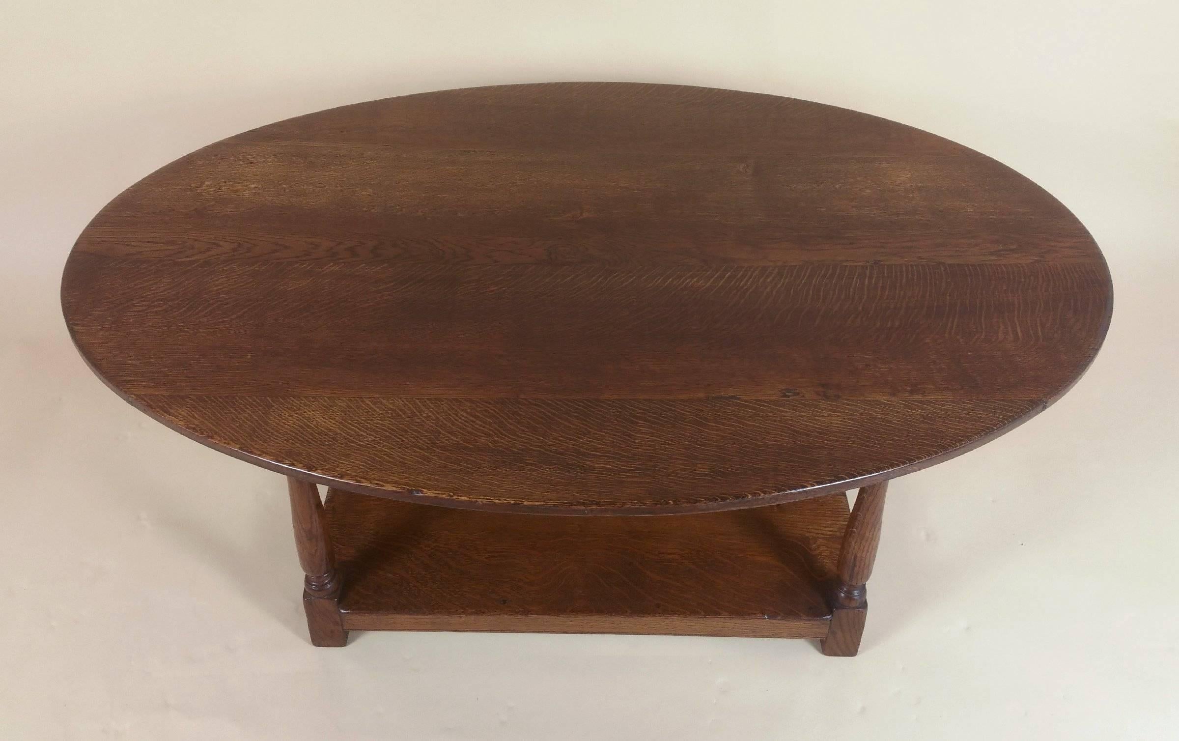 This handsome Edwardian oak oval coffee table features a rectangular under tier on shaped, turned supports. The table has a beautiful and warm patina top and displays a particularly lovely grained pattern. The table measures 48 in – 122 cm wide by