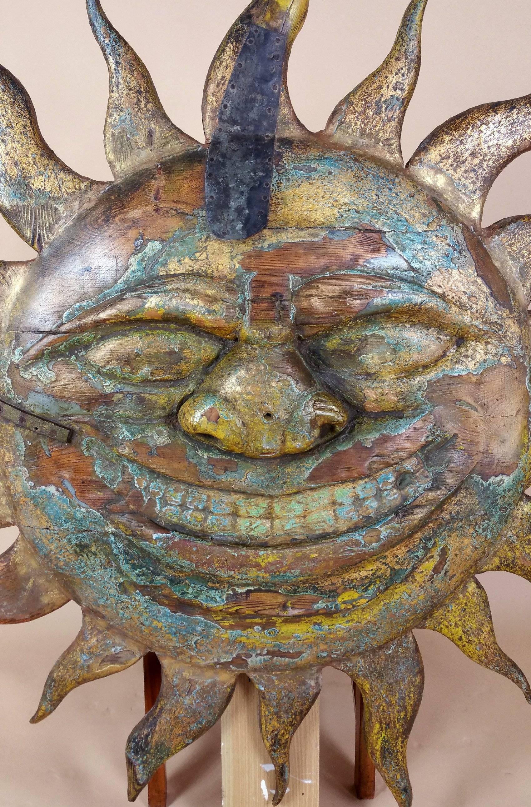 This Superb and rare early 19th century American carved wood large wall plaque is in the form of a sun god, displaying many old layers of paint and gilding back to the pine base. This charming piece features several old blacksmith repairs with metal