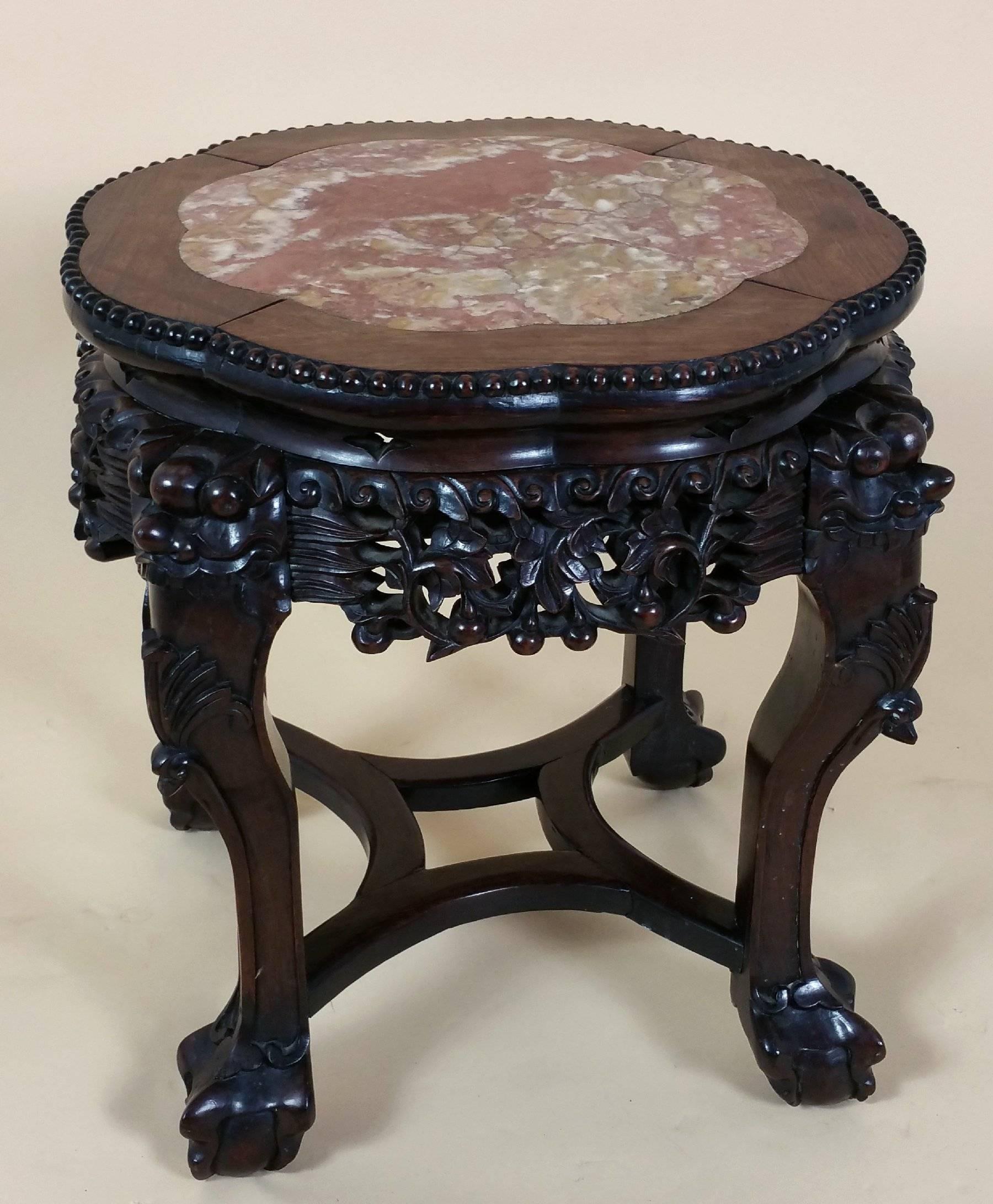 This very decorative 19th century Chinese hardwood stand features an attractive marble inset top and shaped stretcher base. The stand has an ornately carved apron around the outside rim with squared cabriole legs on ball and claw feet. It measures