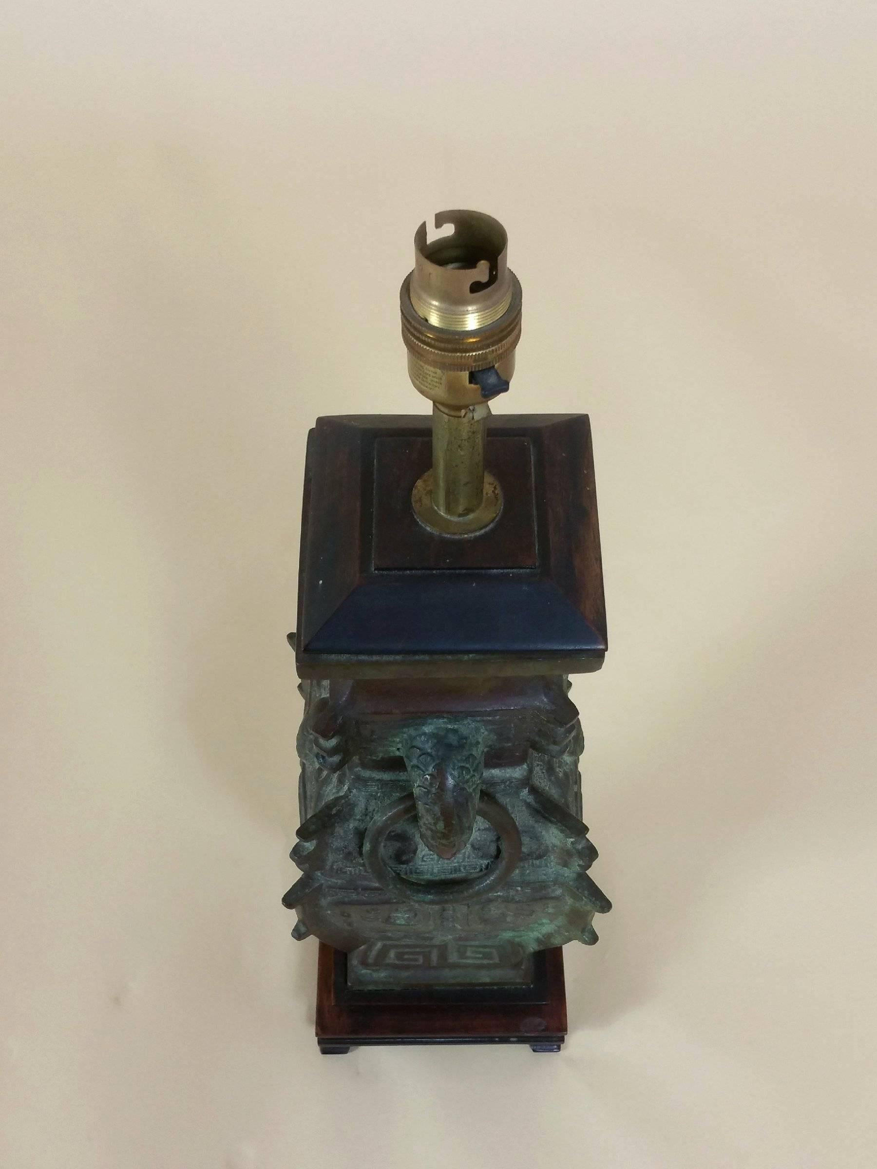 This unique and handsome Chinese archaic style bronze vase has been converted to a table lamp and is circa 1900. The lamp features a lovely patina and is mounted on a hardwood base. It measures 5 ¼ in – 13.3 cm wide, 4 ¾ in – 12 cm deep and 18 ½ in