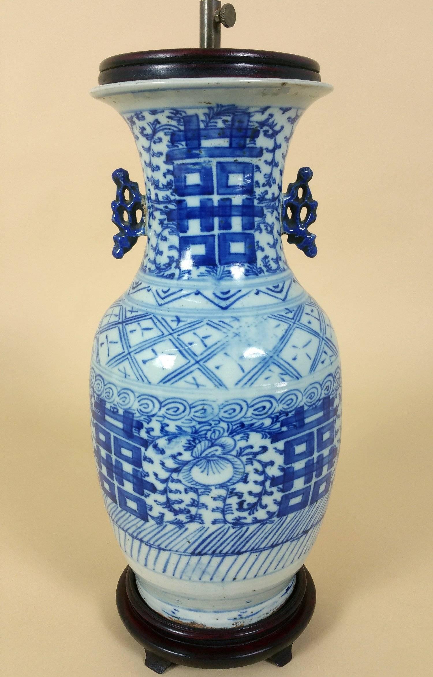 This attractive and well-proportioned late 19th century Chinese blue and white vase which has been converted to a table lamp. The piece features a twin handle design and is mounted on a hardwood stand with a matching cover. The brass fittings