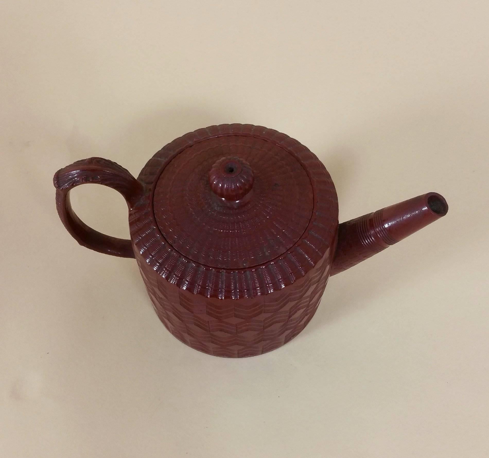 This lovely German pottery teapot is in the manner of Yixing wares, also referred to as purple sand. It features a basket weave and chevron incised decoration, with an impressed seal mark on the base. It measures 3 ¾ in -9.5 cm in diameter and 3 ¾