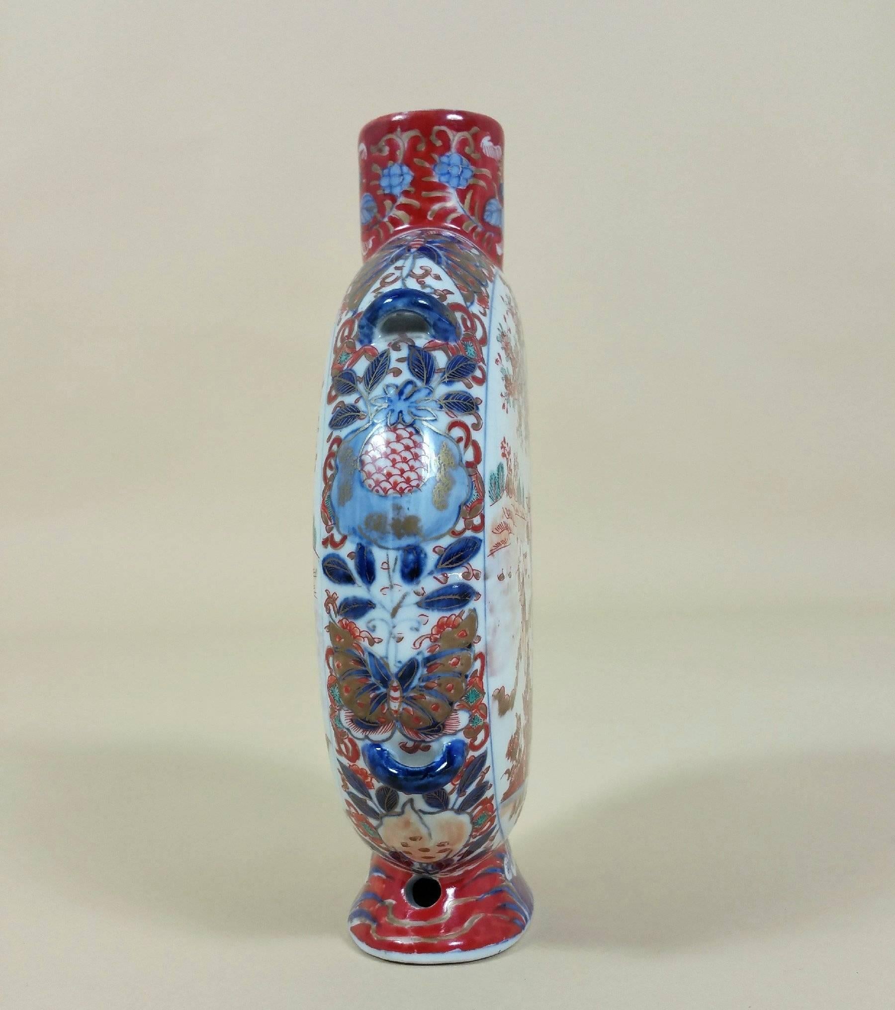 This lovely Japanese Koransha pottery moon flask is painted in the Imari palette depicting whimsical characters in an outdoor setting around cherry blossom foliage. Koransha was founded as a maker and exporter of Arita porcelain in 1875 by Eizaemon