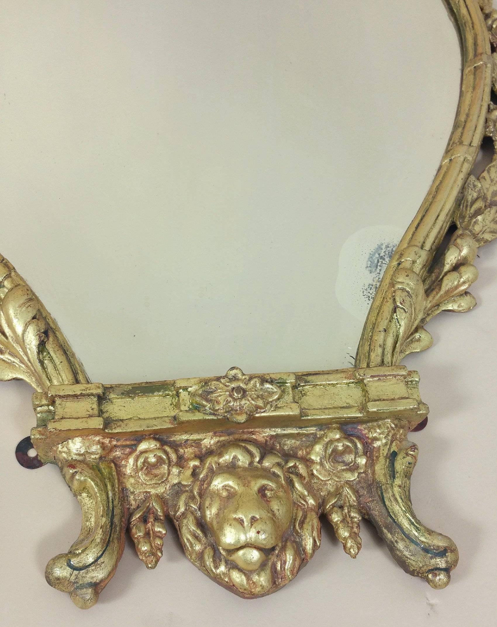 This magnificent and elegant pair of mid-19th century neoclassical gilt wall mirrors are nicely shaped and feature an ornate carved floral border detail with lion mask centerpieces. Each mirror measures 26 in – 66 cm wide, 3¾ in – 9.5 cm deep and 41