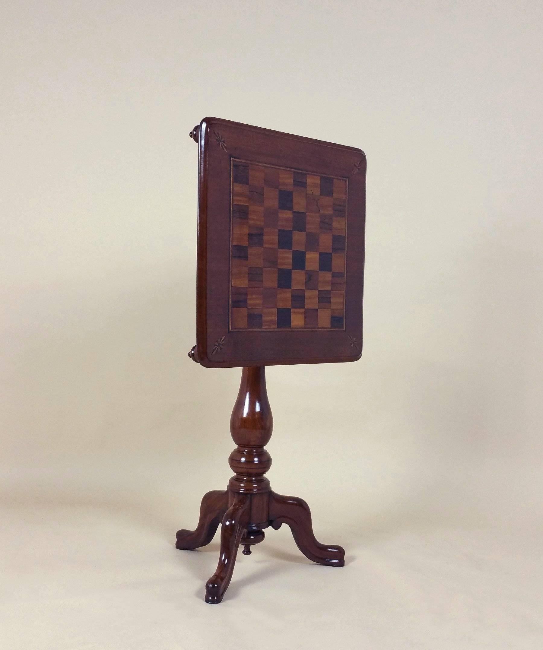 This very attractive and delightful Victorian mahogany tilt-top chess table features a satinwood and rosewood check board inlay design and corner detailing, set on a tripod support with very ornate, turned corner decoration underneath. The tabletop