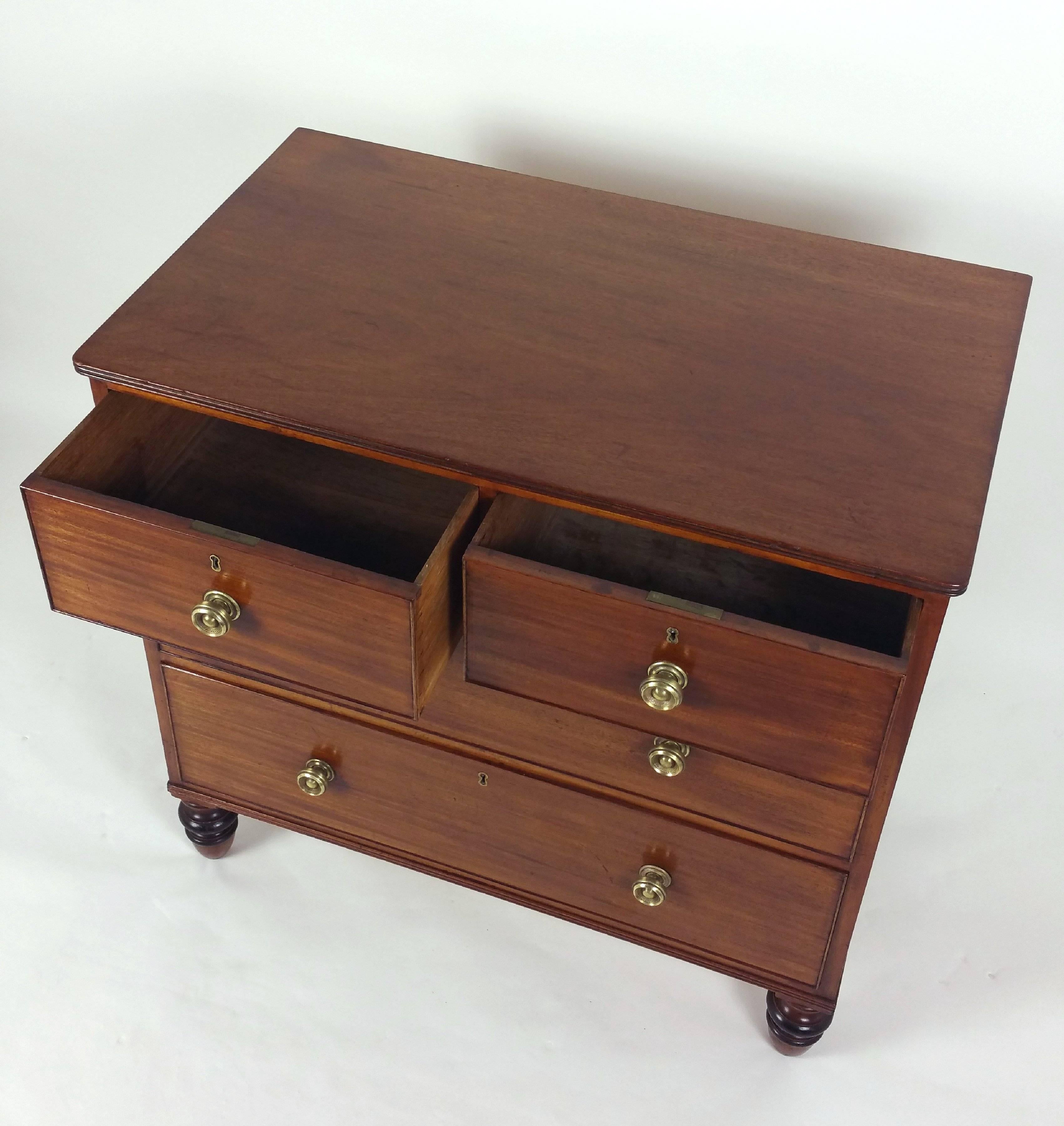 This Regency figured mahogany low chest of drawers features two short drawers over two long drawers, with the original brass knob handles and ebonized highlights. The chest is supported on very attractive turned legs with rounded front corners. It