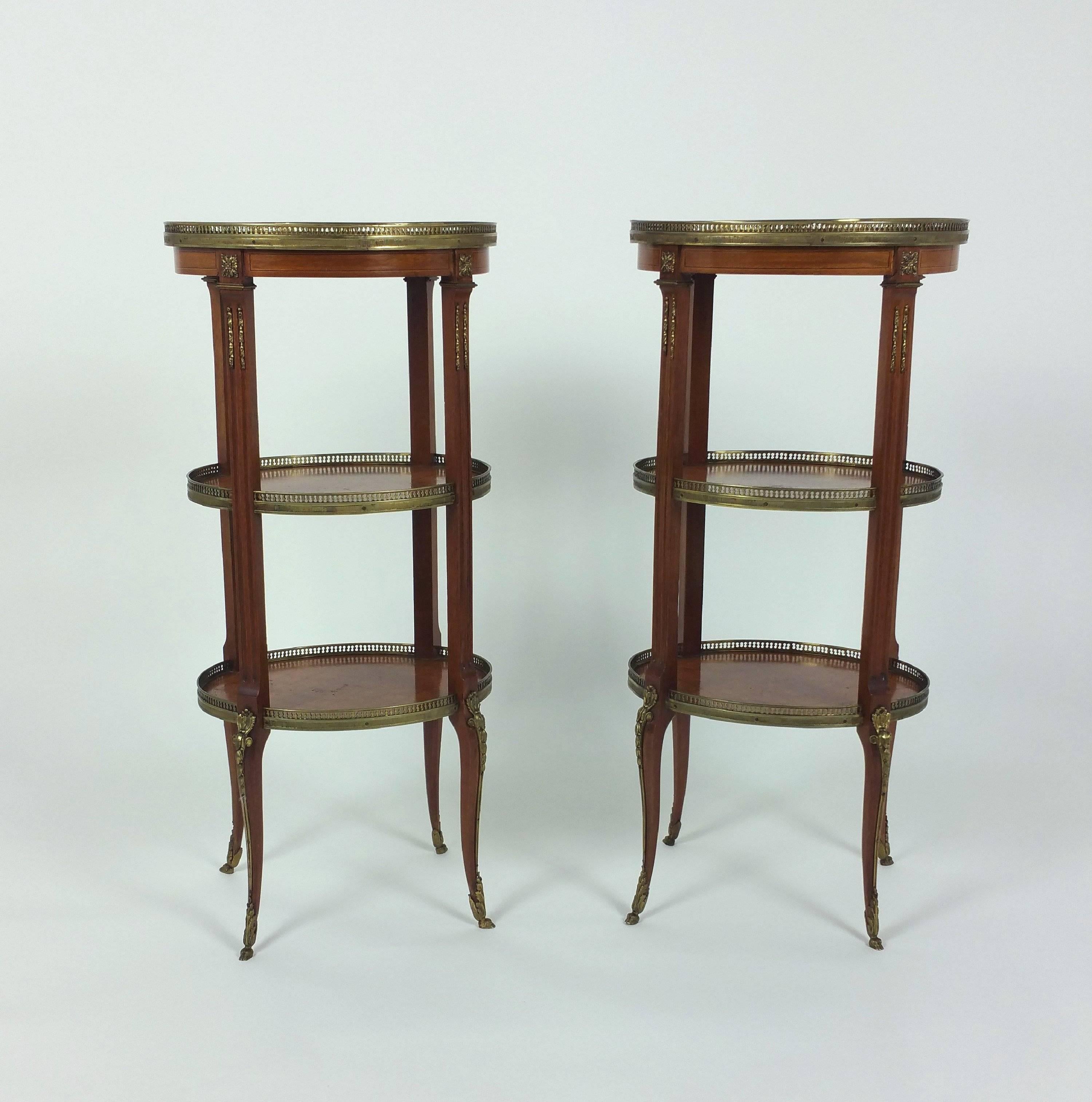 This beautiful pair of French marquetry inlaid kingwood étagères feature three tiers, each with a gilt brass gallery and gilt brass mounts on the top and bottom. The étagères are supported on slender shaped cabriole legs and finish with delicate