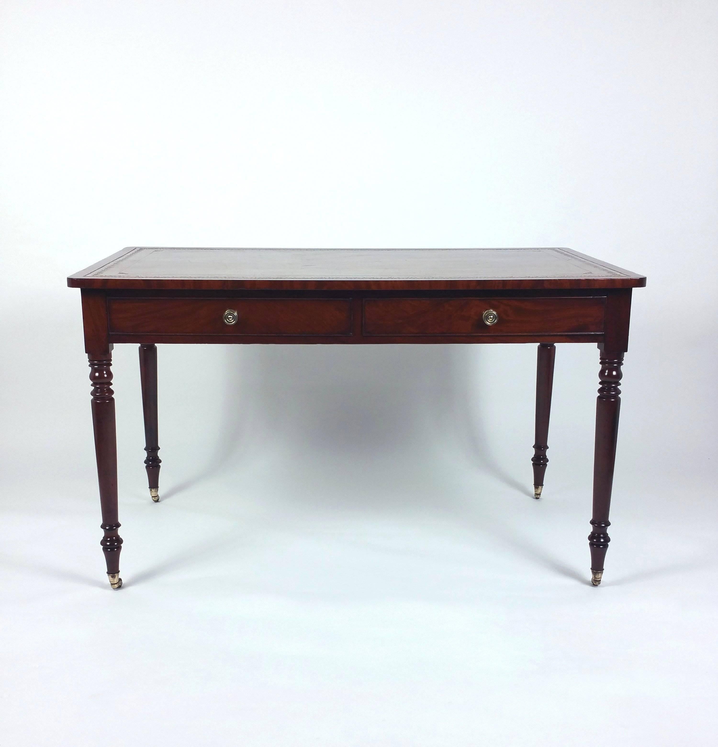 This very handsome Regency mahogany library table features working drawers on one side and two matching faux drawers on the other side. The table has the original leather top and stands on slender turned supports with brass castors. It measures 50