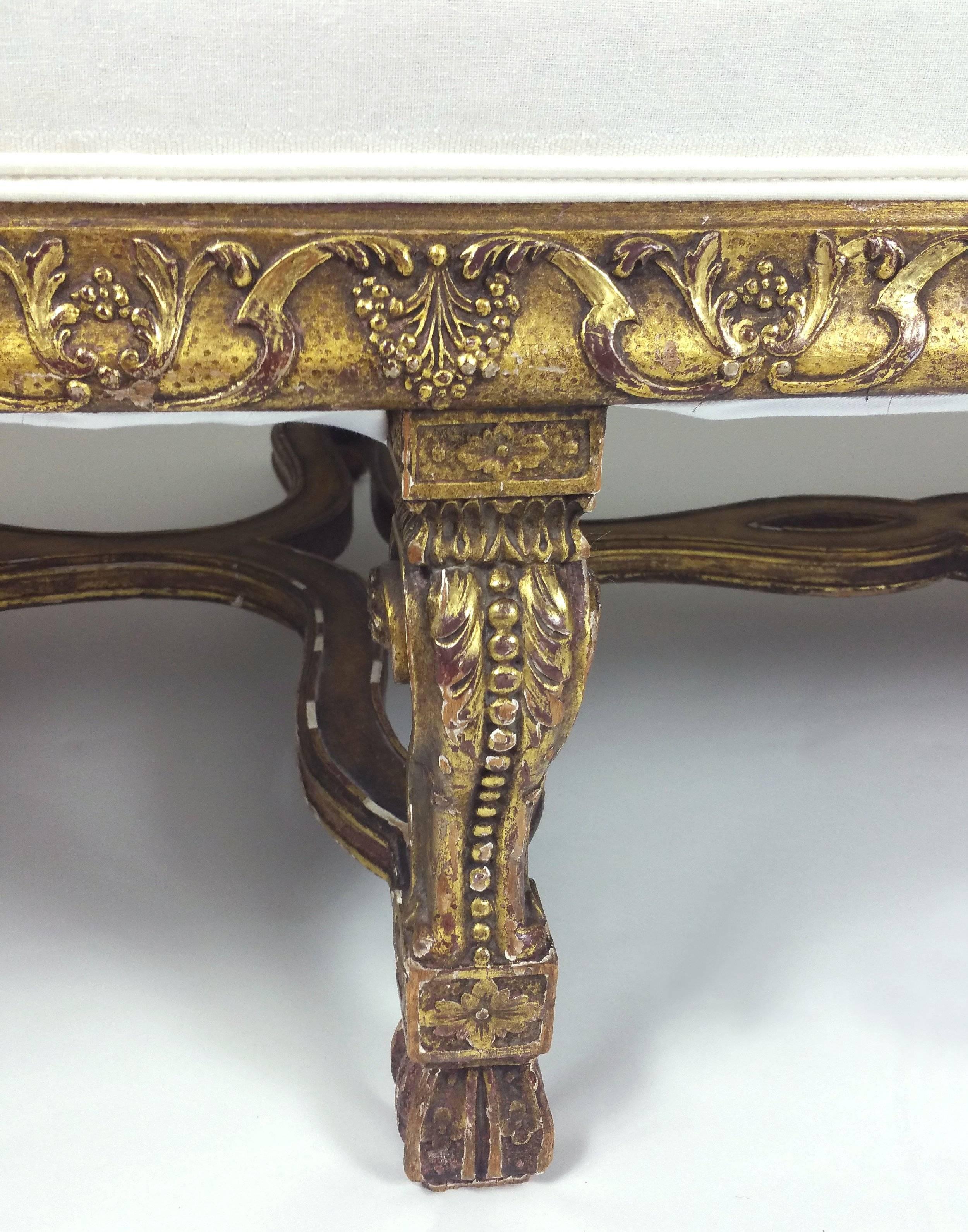 This superb and impressively sizes William and Mary styled carved giltwood settee features exaggerated, scrolled armrest ends and a pierced, shaped under tier. The detailed carving on the base of the seat runs around the entire settee including the