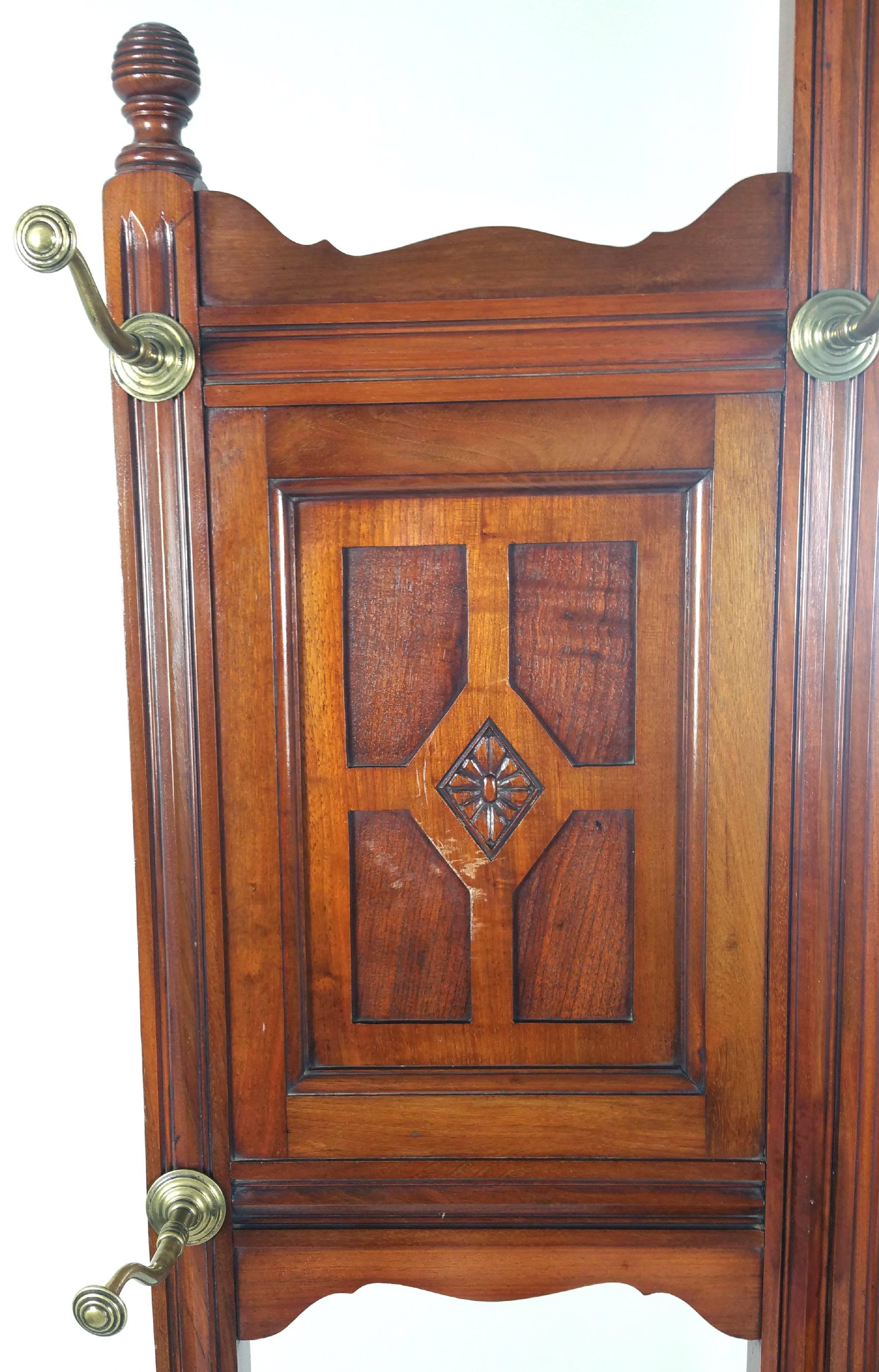 This well-proportioned and splendid Victorian walnut hallstand features a bevelled mirror back and is inset with a splash back of decoratively patterned tiles. The curved and detailed brass coat hooks and drawer pull are original and the wood