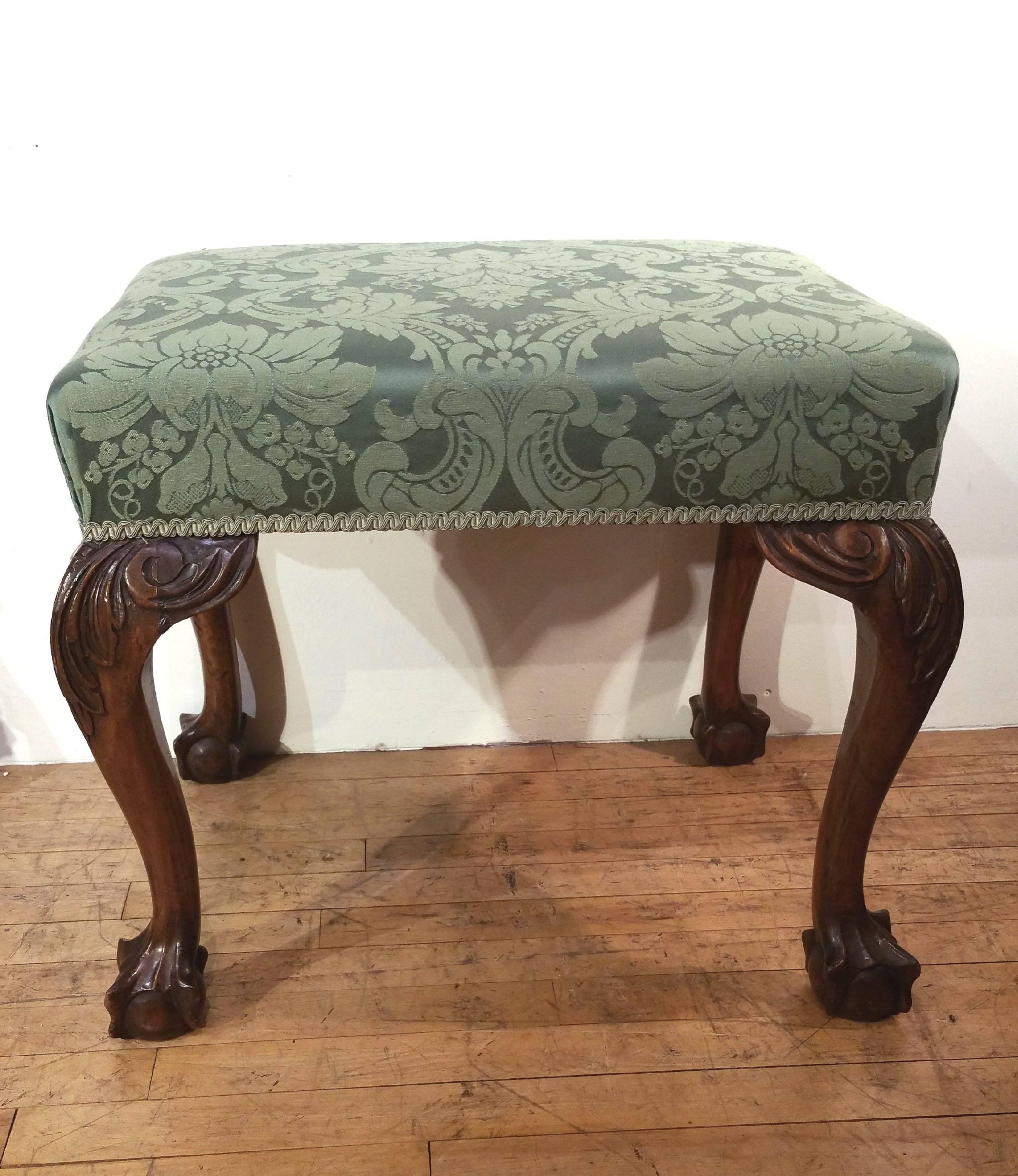 This elegant and well-proportioned carved walnut English stool is in the Chippendale style with ornately carved acanthus leaves on cabriole legs with ball and claw feet. The stool measures 23 ½ in – 59.7 cm wide by 18 ½ in – 47 cm deep with a height