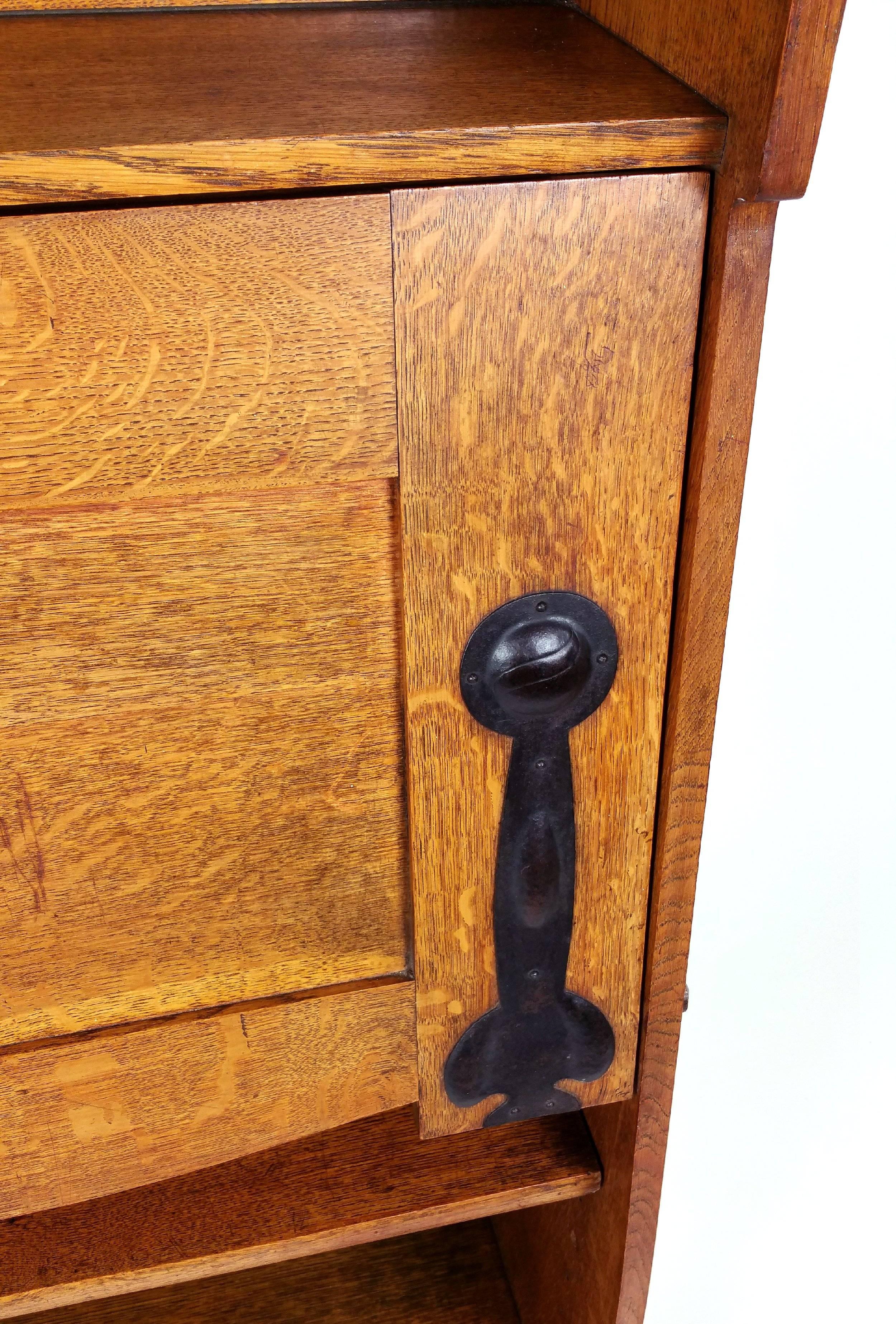 This delightful and very attractive late 19th Century Arts and Crafts oak bureau is attributed to Liberty’s of London. The bureau features decorative iron hinges and lock plate, with lovely pierced detailing around the top gallery. The fold down