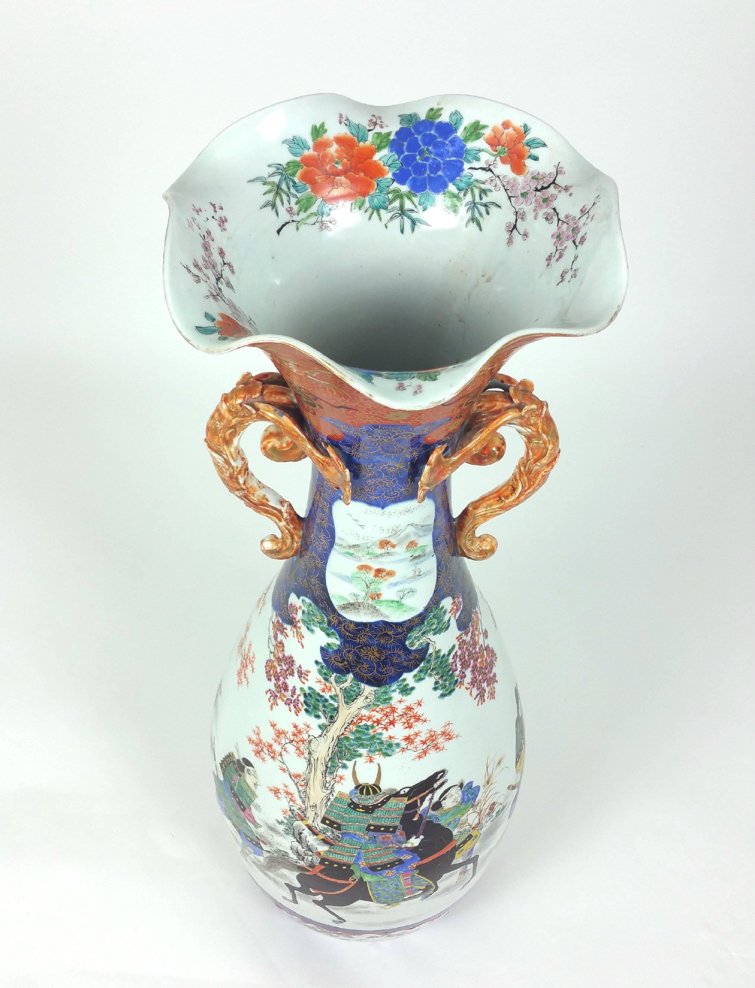 This large and impressive 19th century Japanese twin handled vase is hand-painted in enamels with samurai warriors and horses with floral borders in stunning detail and vivid color, with markings to the base. It measures 12 in – 30.5 cm in diameter
