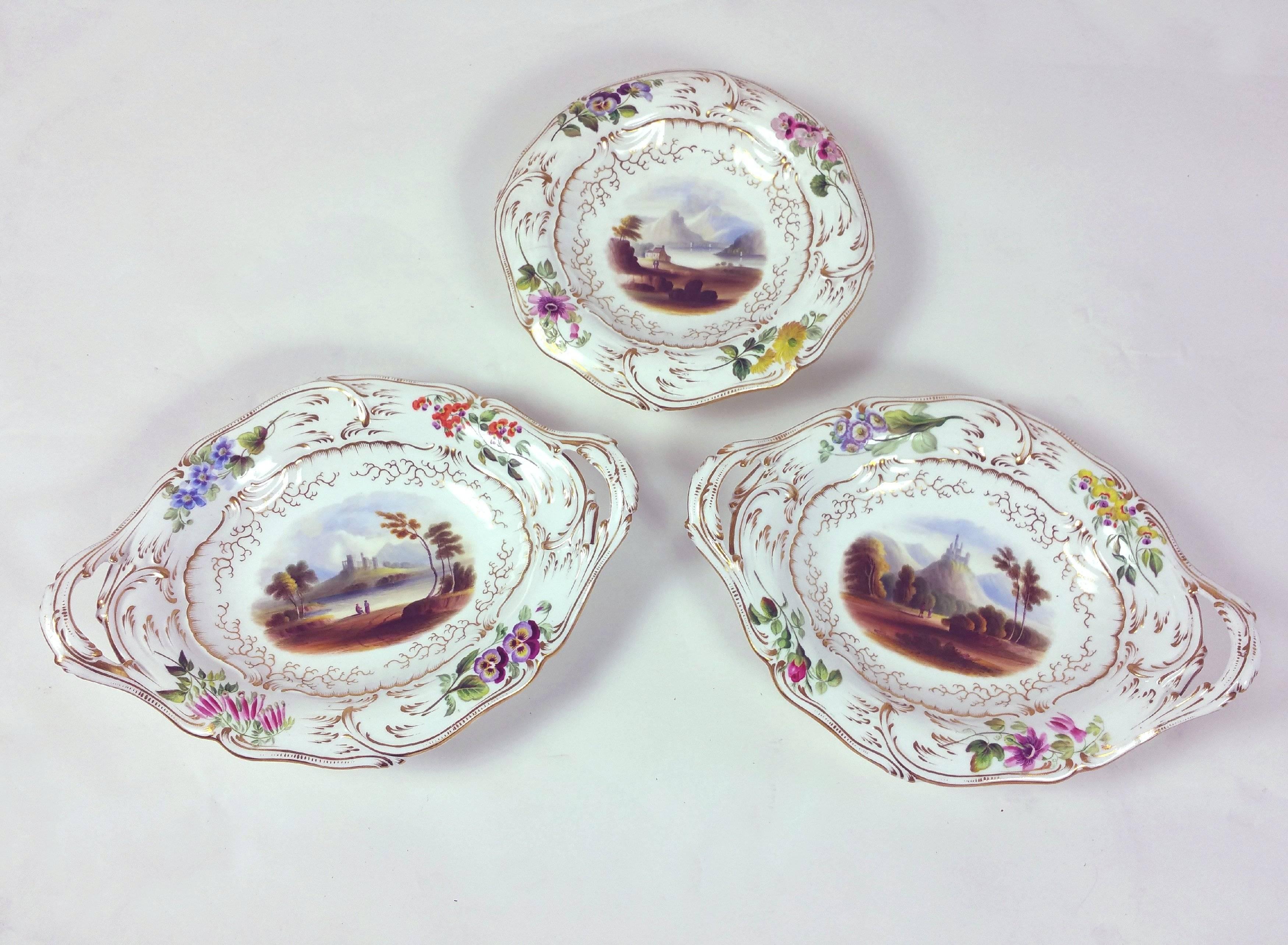 This stunning and beautifully hand-painted 19th century, English pottery dessert service features a finely detailed floral border with gold leaf and a central image of various English outdoor scenes of castles and rural settings. The set consists of